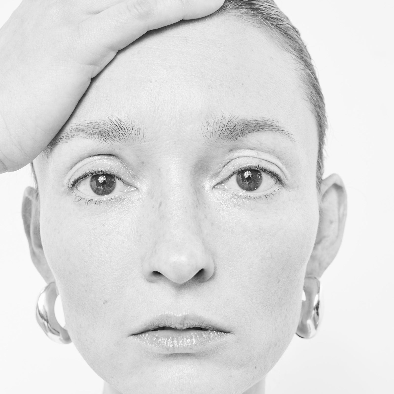 Model wearing AGMES 14k gold vermeil round sculptural Large Celia Hoops. Black and white image.
