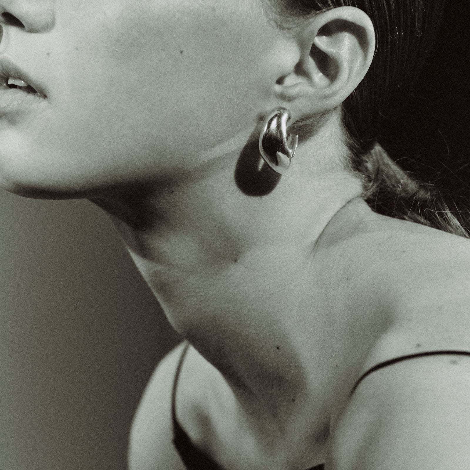 Model wearing AGMES .925 sterling silver sculptural round Large Celia Hoops. Black and white image.