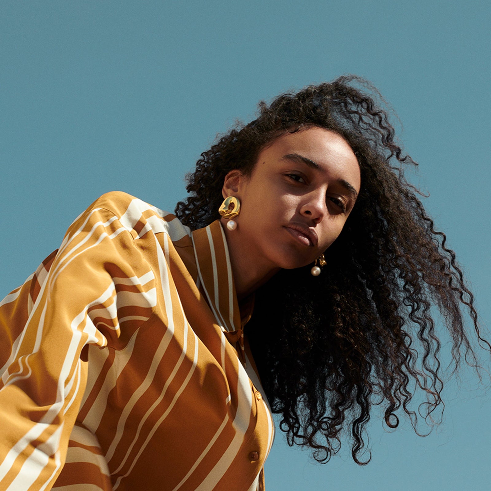 Woman wearing AGMES 18k gold vermeil sculpted Gertrude pearl drop earrings. Simone Bodmer-Turner.