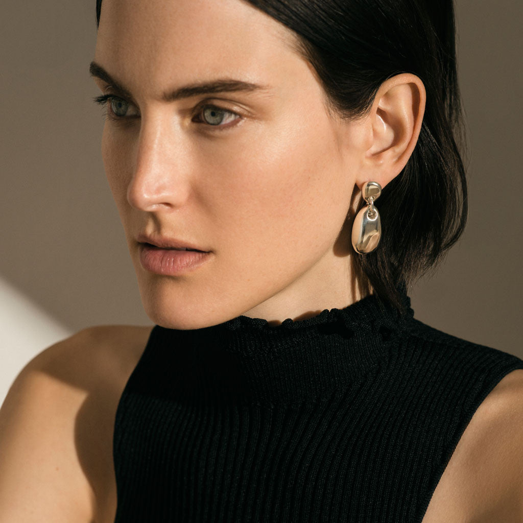 Woman wearing AGMES 0.925 sterling silver sculpted round drop earrings.