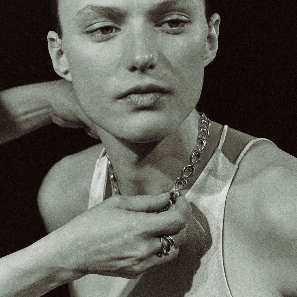 Model wearing AGMES .925 sterling silver sculptural link Thin Tilda Necklace and white top. Black and white image.