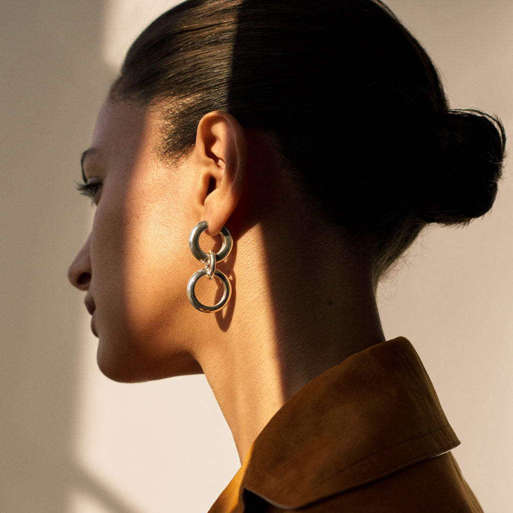 Woman wearing AGMES 0.925 sterling silver hoop earrings with circular drop.