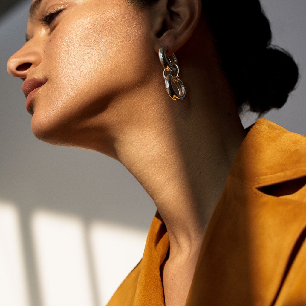 Woman wearing AGMES 0.925 sterling silver hoop earrings with circular drop.