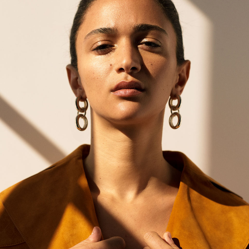Woman wearing AGMES 0.925 sterling silver hoop earrings with circular drop.