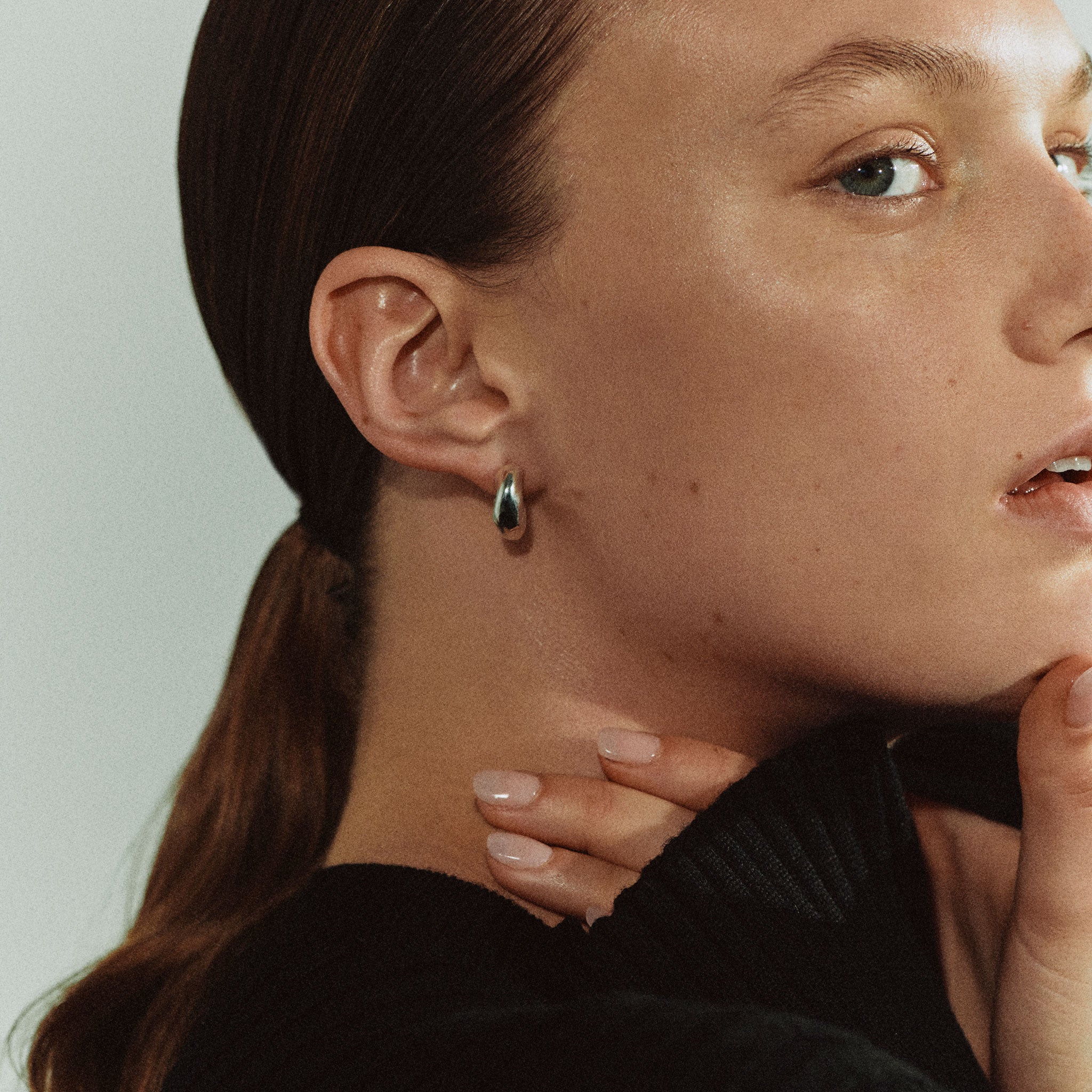 Woman wearing AGMES 0.925 sterling silver thick hoop earrings.