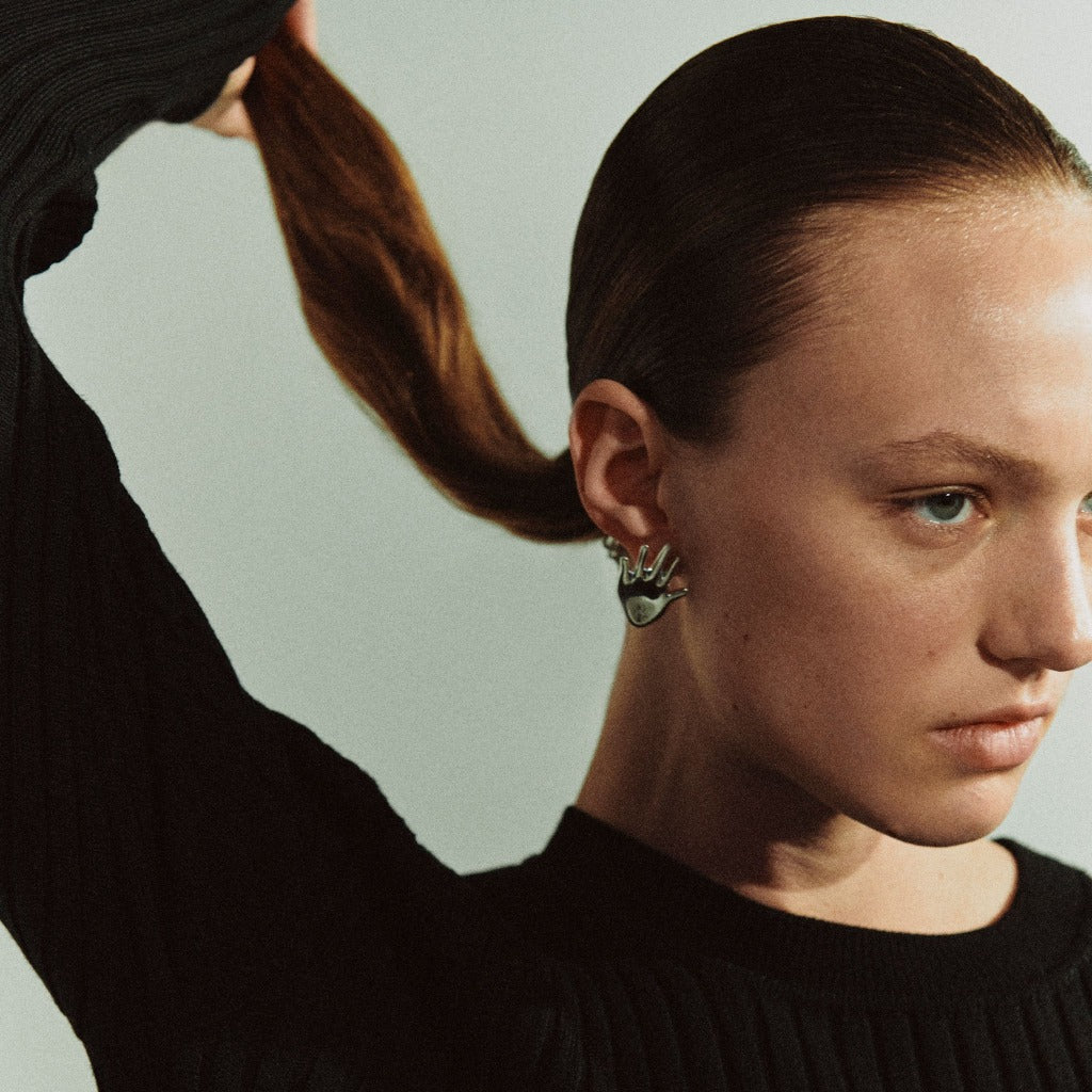 Woman wearing AGMES 0.925 sterling silver abstract hand earrings.