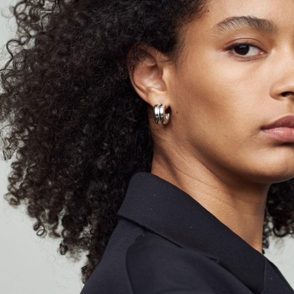 Woman wearing AGMES 0.925 sterling silver double ridged small hoop earrings.