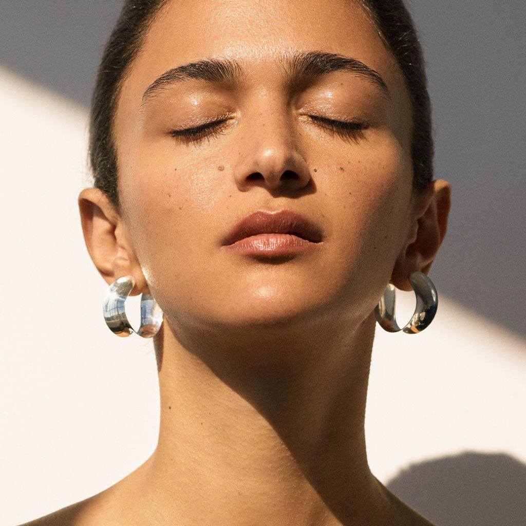 Woman wearing AGMES 0.925 sterling silver twist hoop earrings.