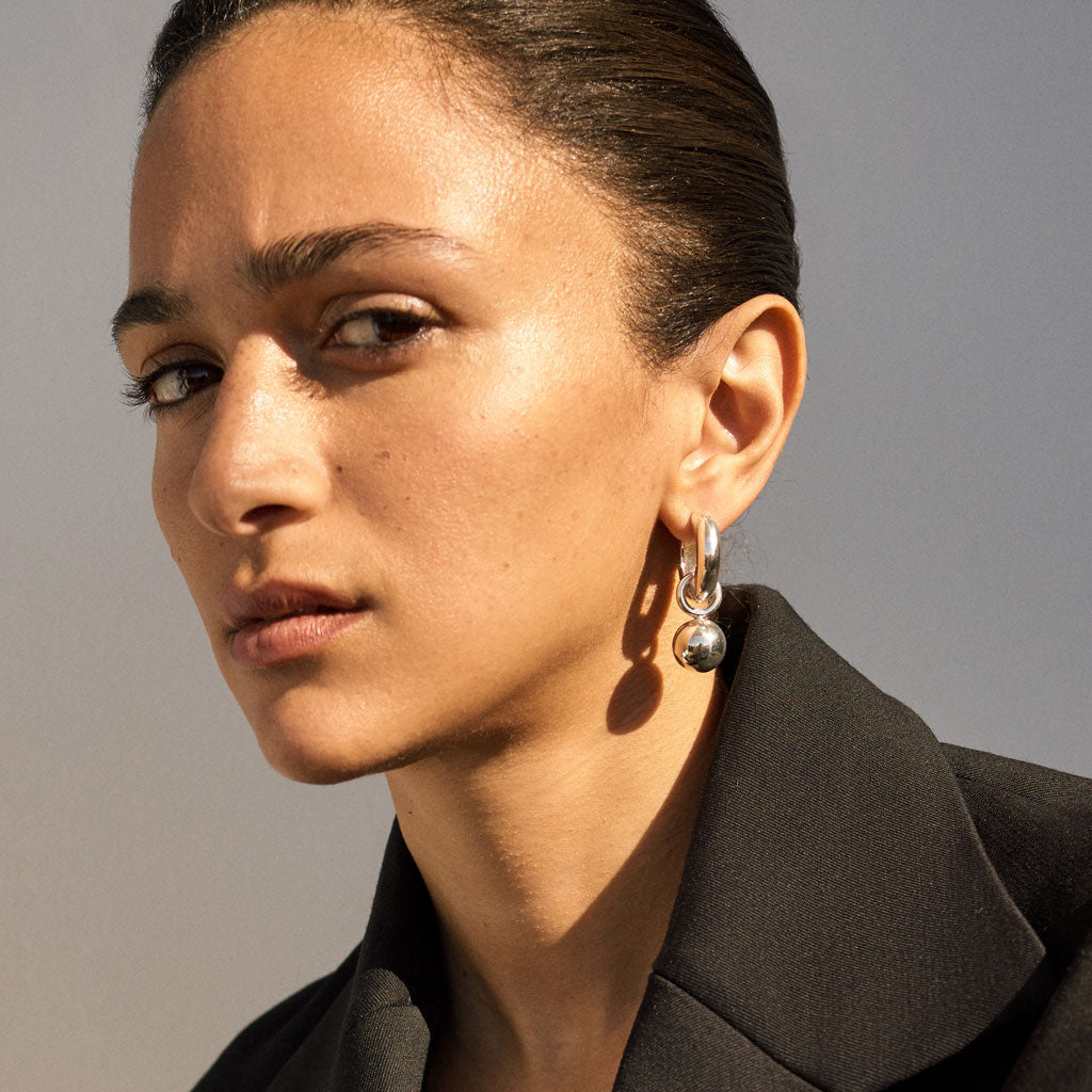 Woman wearing AGMES 0.925 sterling silver Sonia hinged hoop earrings.