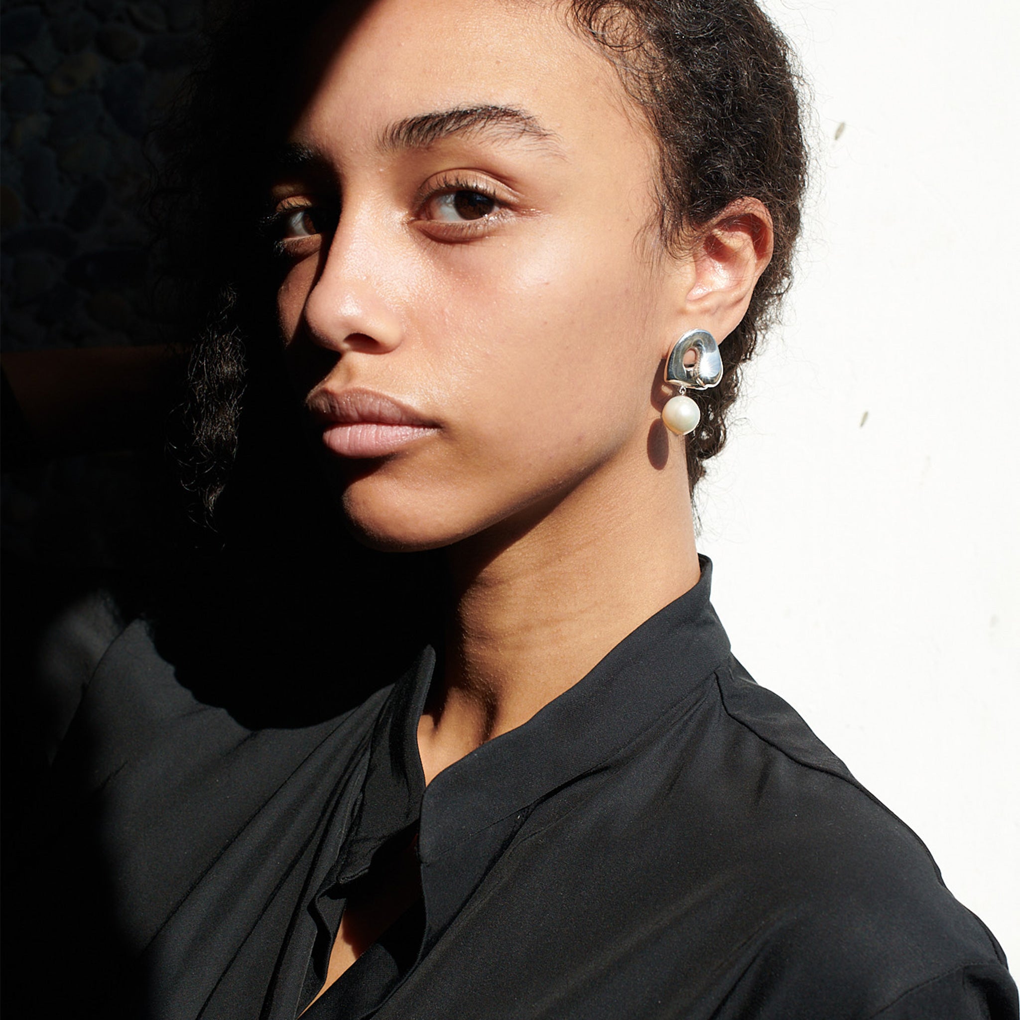 Woman wearing AGMES 0.925 sterling silver sculpted Gertrude pearl drop earrings. Simone Bodmer-Turner.