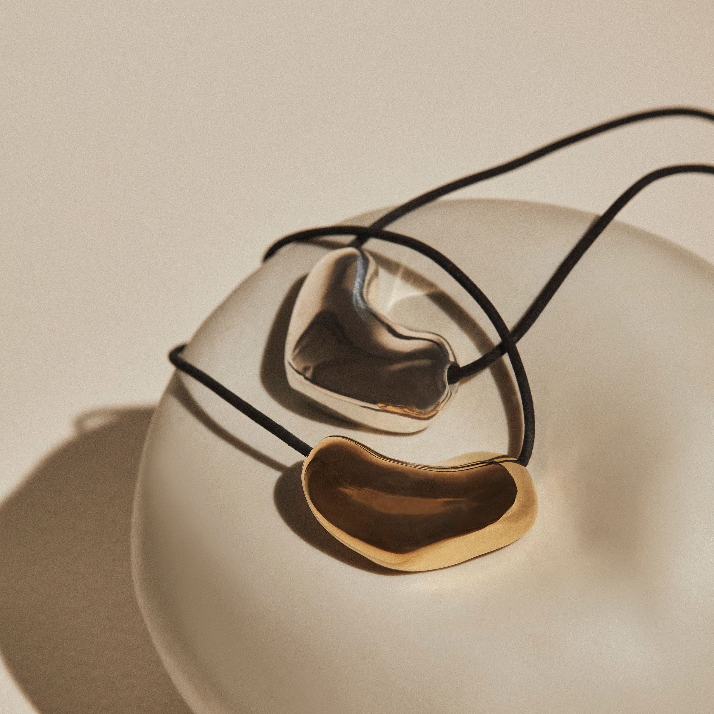 AGMES 18k Gold Vermeil Sculpted Heart Pendant and .925 Sterling Silver Sculpted Heart Pendant on Black Suede Cord.