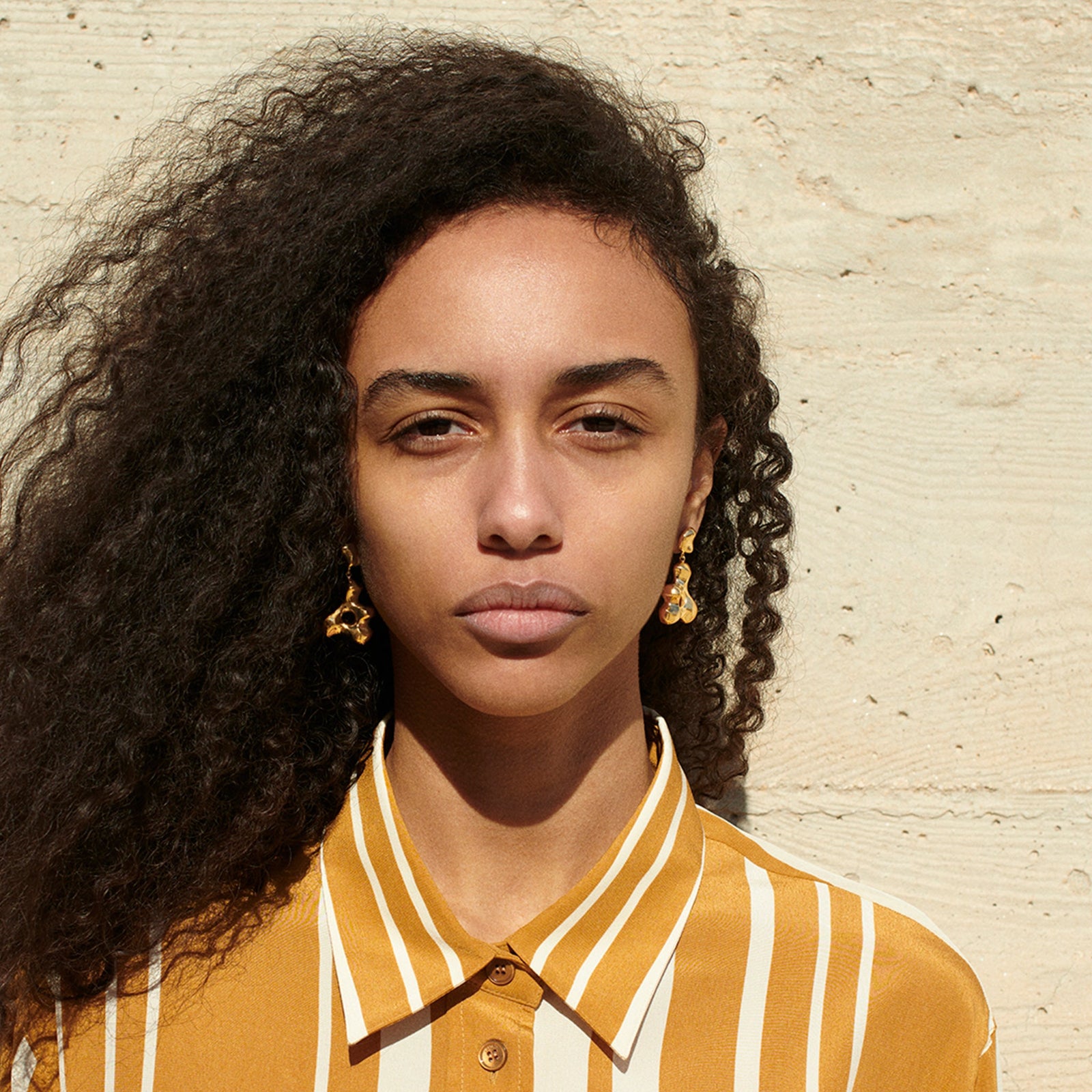 Woman wearing AGMES 18k gold vermeil sculpted drop earrings. Simone Bodmer-Turner.