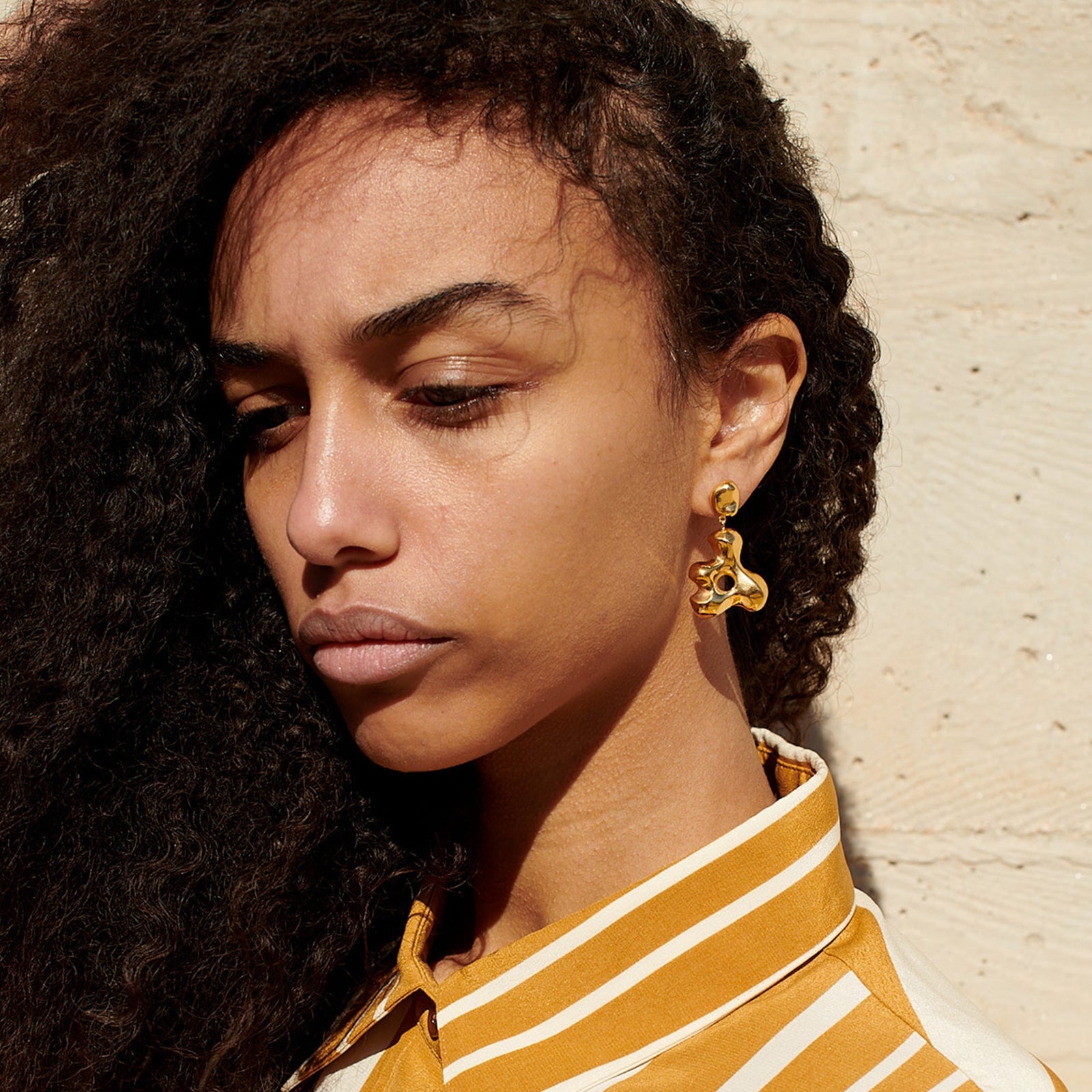 Woman wearing AGMES 18k gold vermeil sculpted drop earrings. Simone Bodmer-Turner.