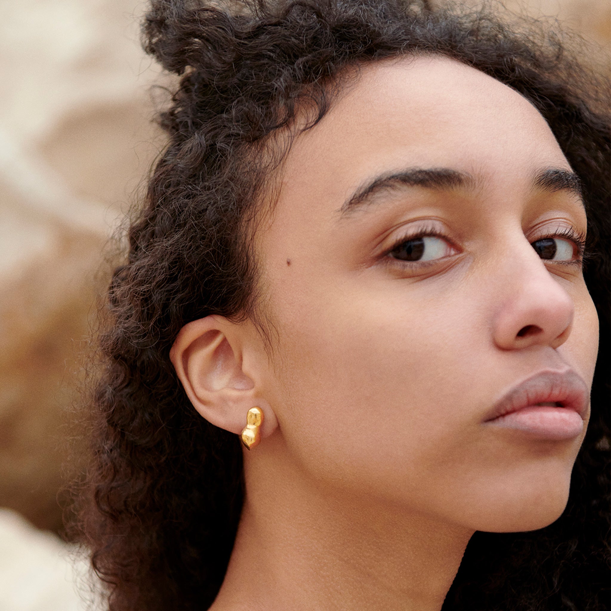 Woman wearing AGMES 18k gold vermeil sculpted small bubble hoop earrings. Simone Bodmer-Turner.