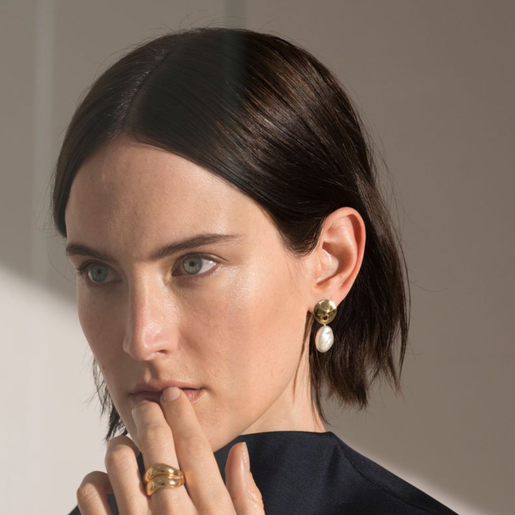 Woman wearing AGMES 18k gold vermeil small round earrings with freshwater pearl drop.
