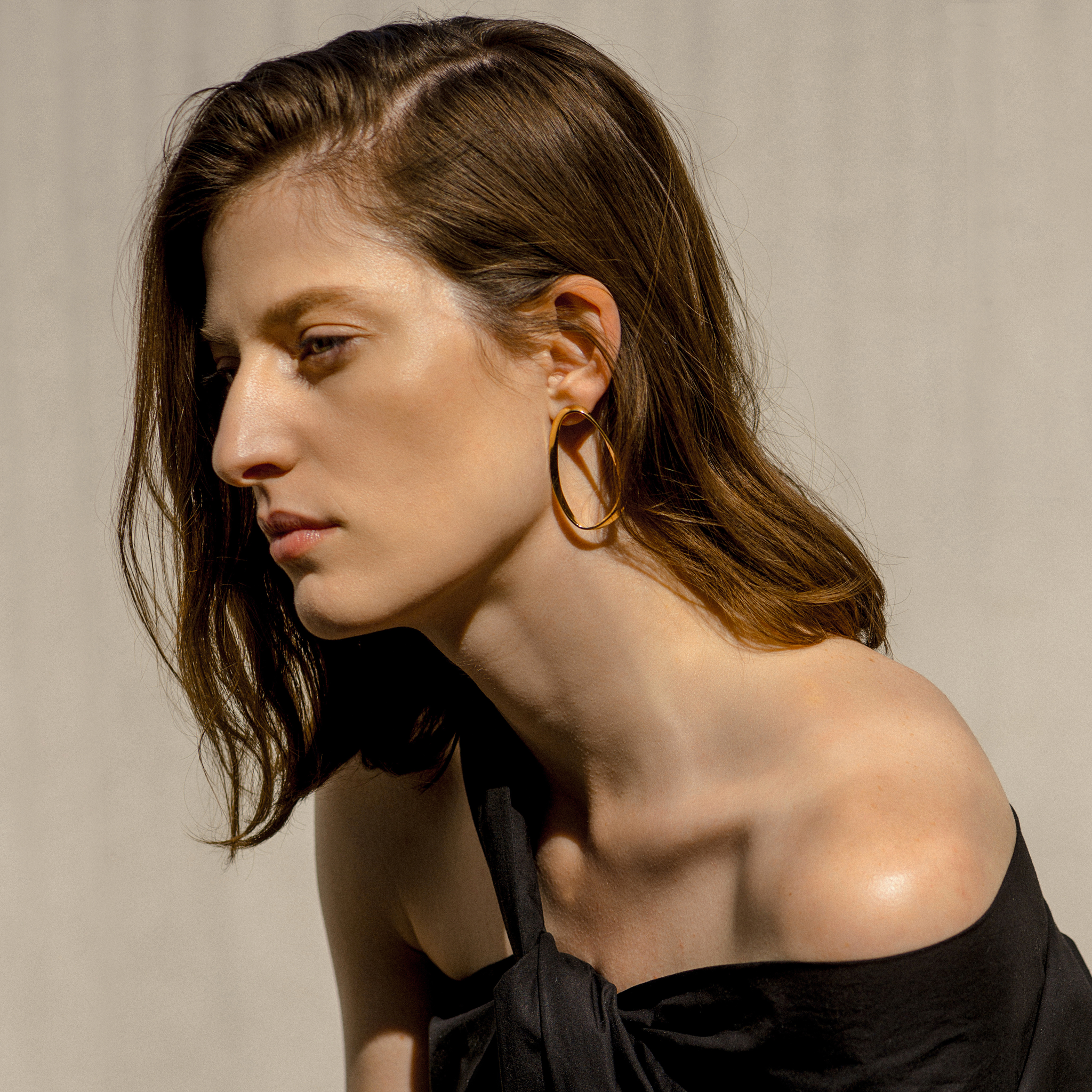 Woman wearing AGMES 18k gold vermeil twisted round oval earrings.