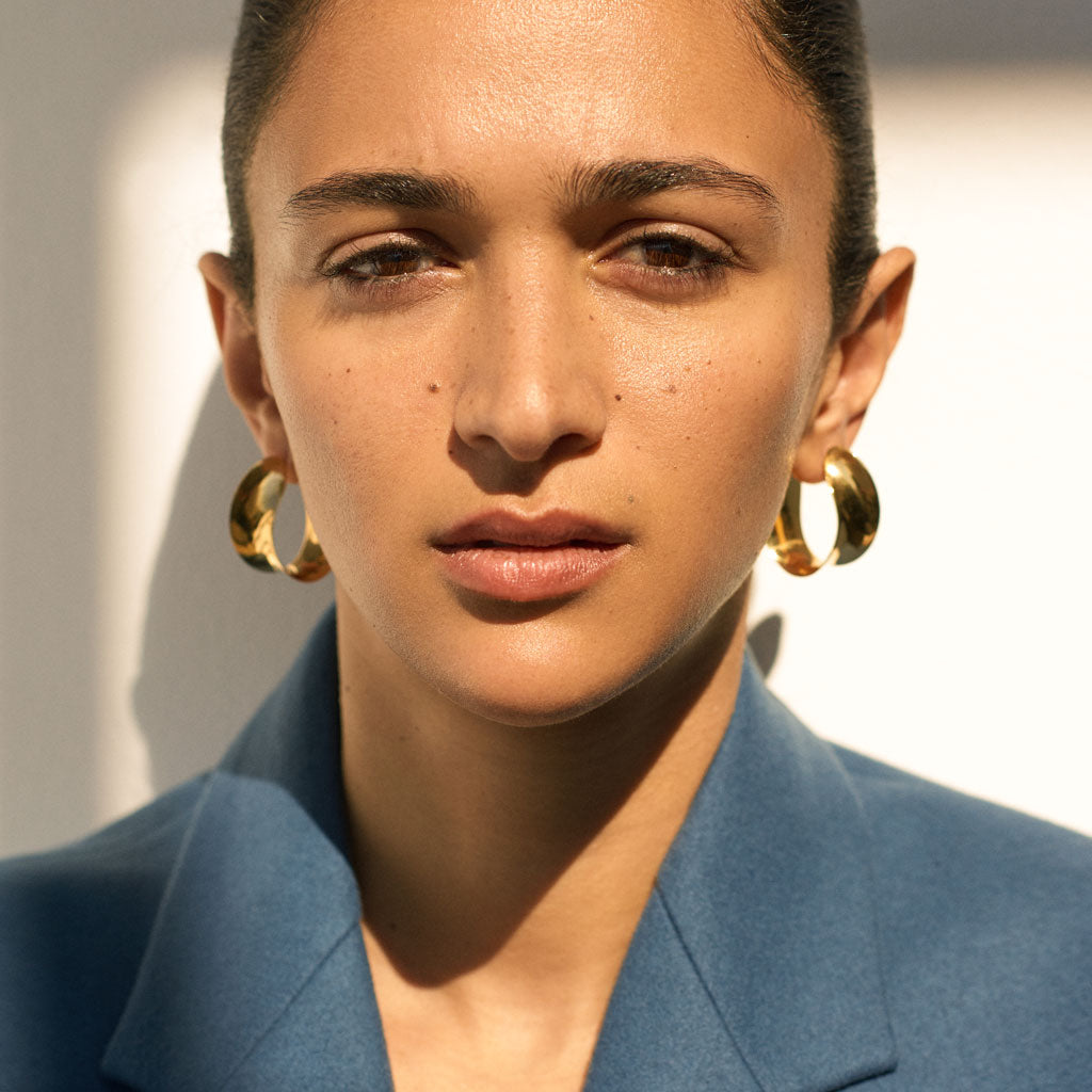 Woman wearing AGMES 18k gold vermeil twist hoop earrings.