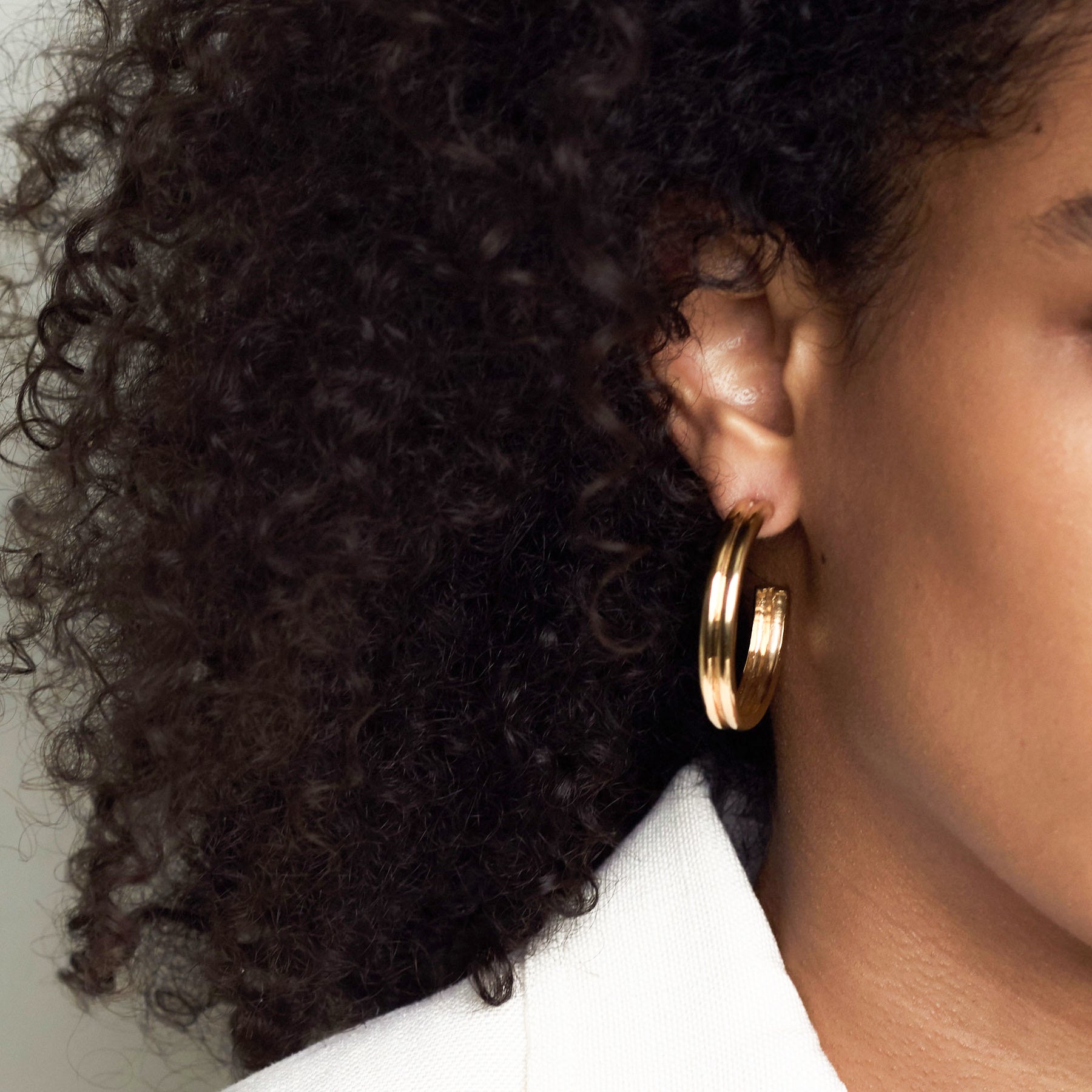Woman wearing AGMES 18k gold vermeil double ridged large hoop earrings.