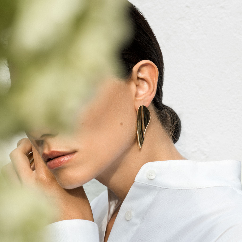 Woman wearing AGMES 18k gold vermeil long sculpted earrings.