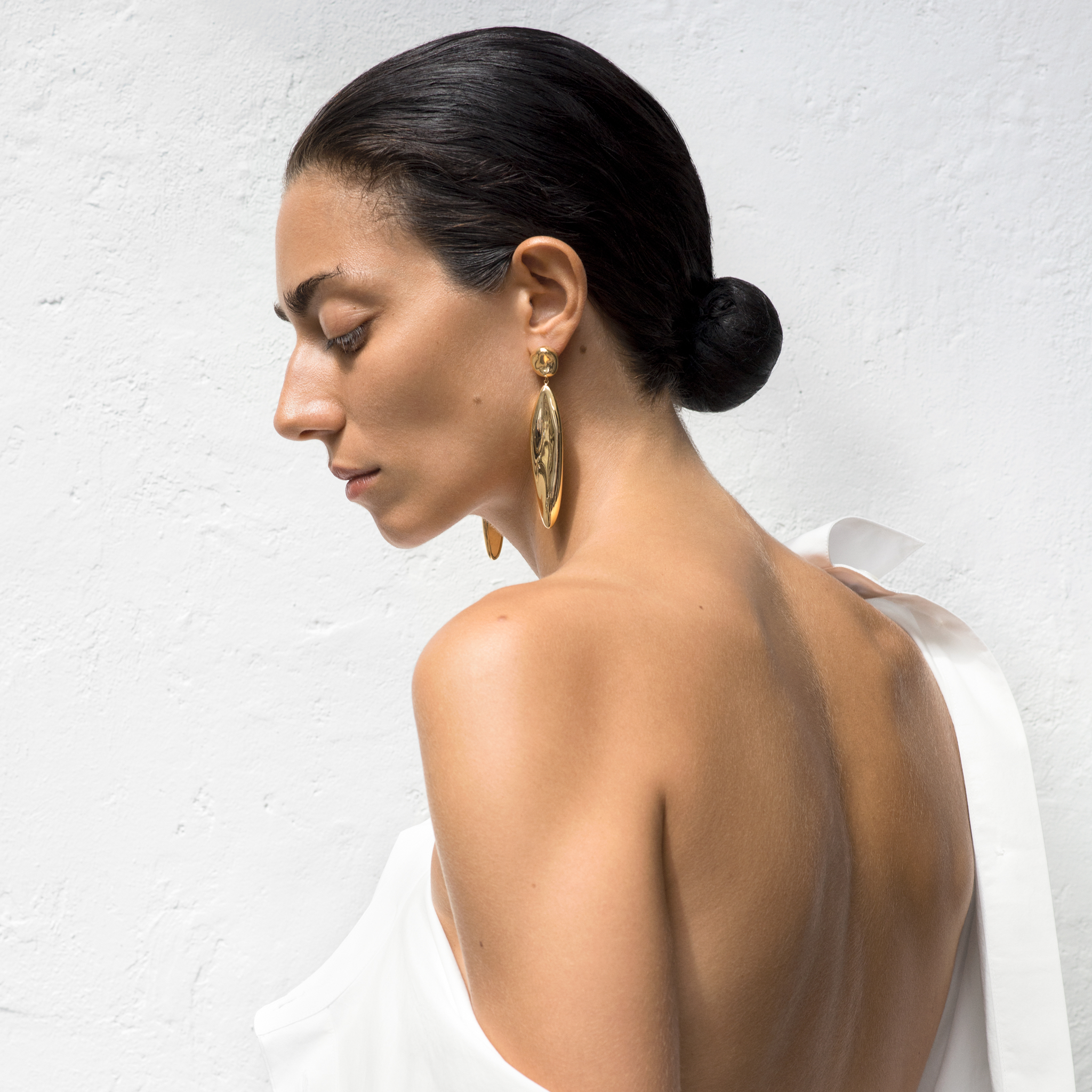 Woman wearing AGMES 18k gold vermeil sculpted drop earrings.