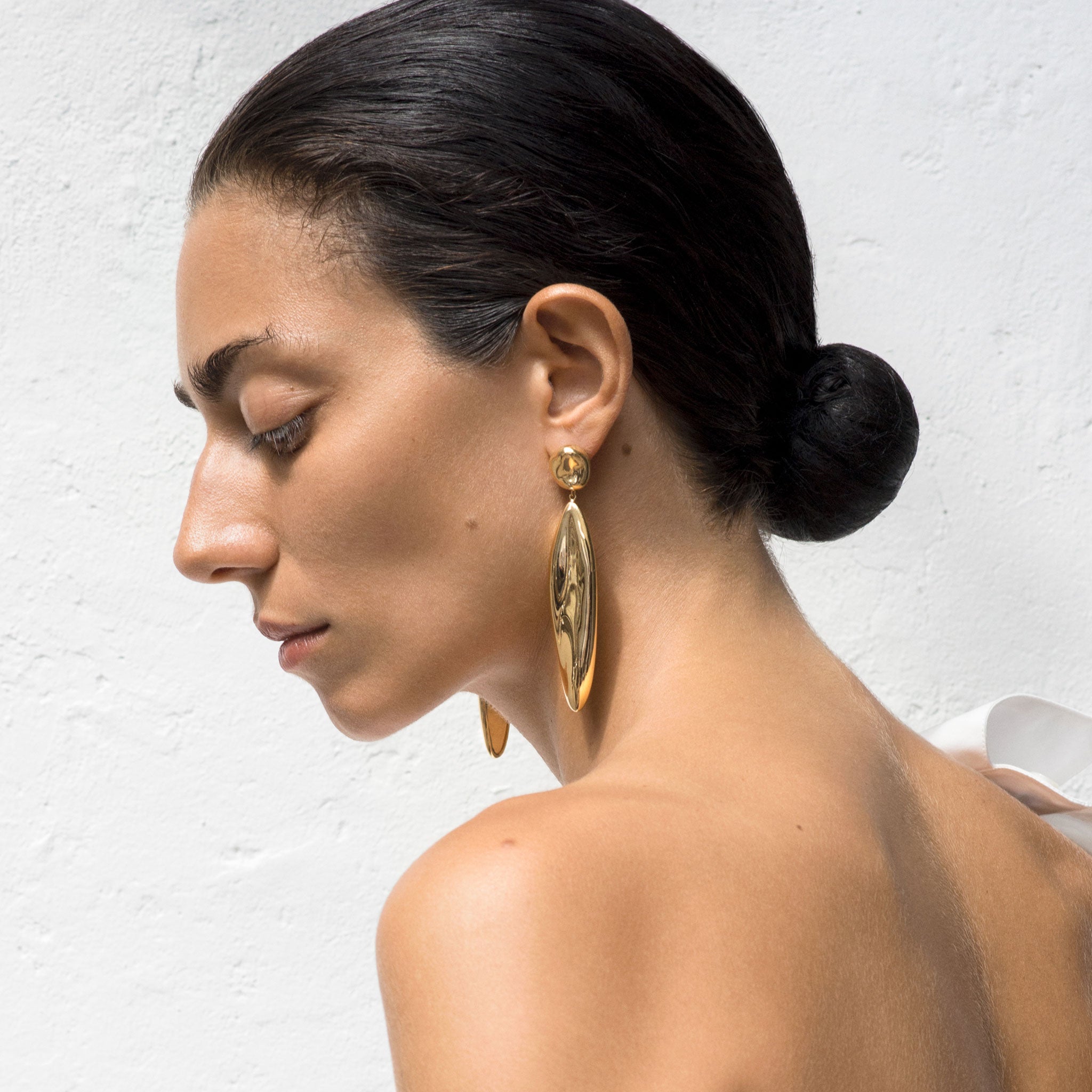 Woman wearing AGMES 18k gold vermeil sculpted drop earrings.