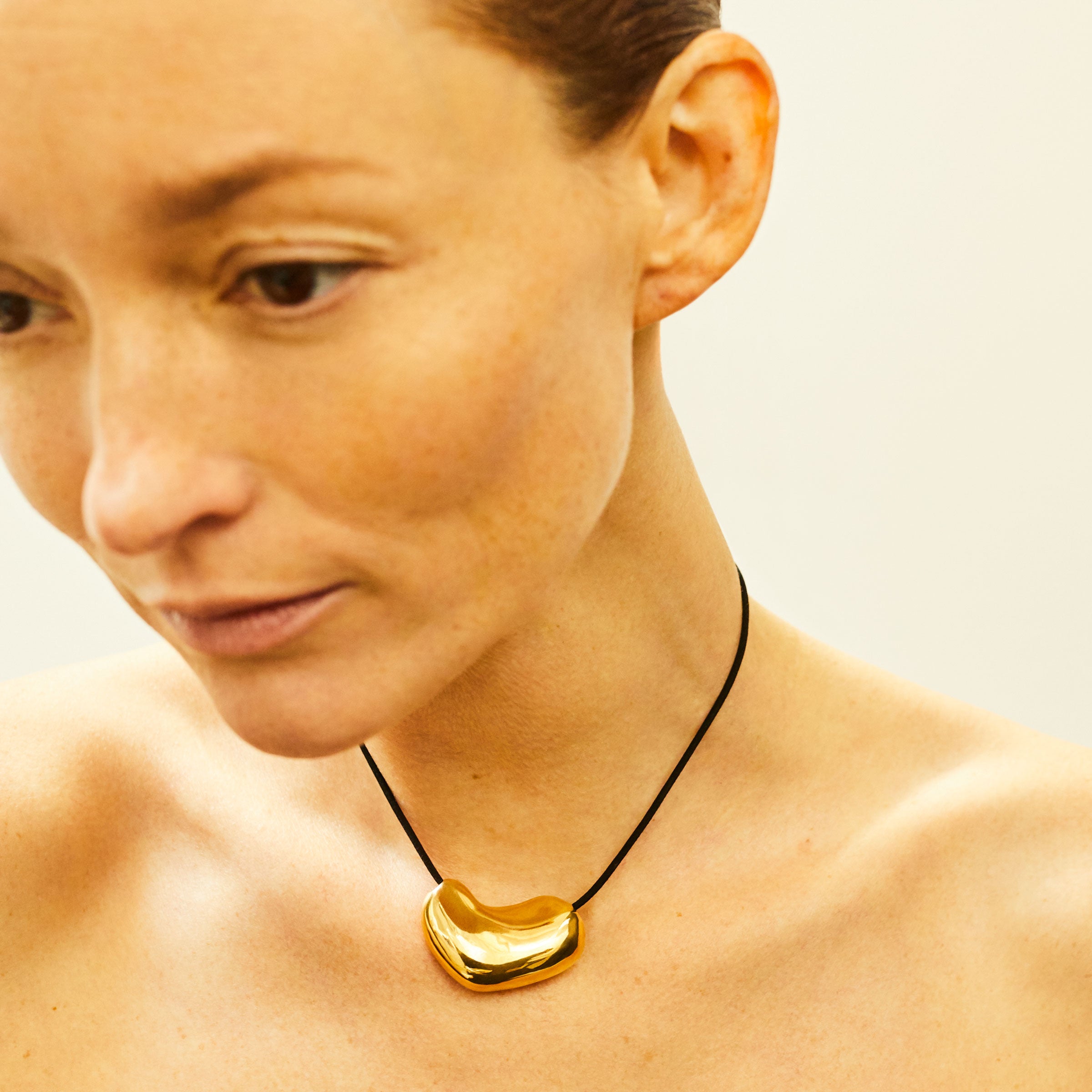 Woman wearing AGMES 18k Gold Vermeil Sculpted Heart Pendant on Black Suede Cord