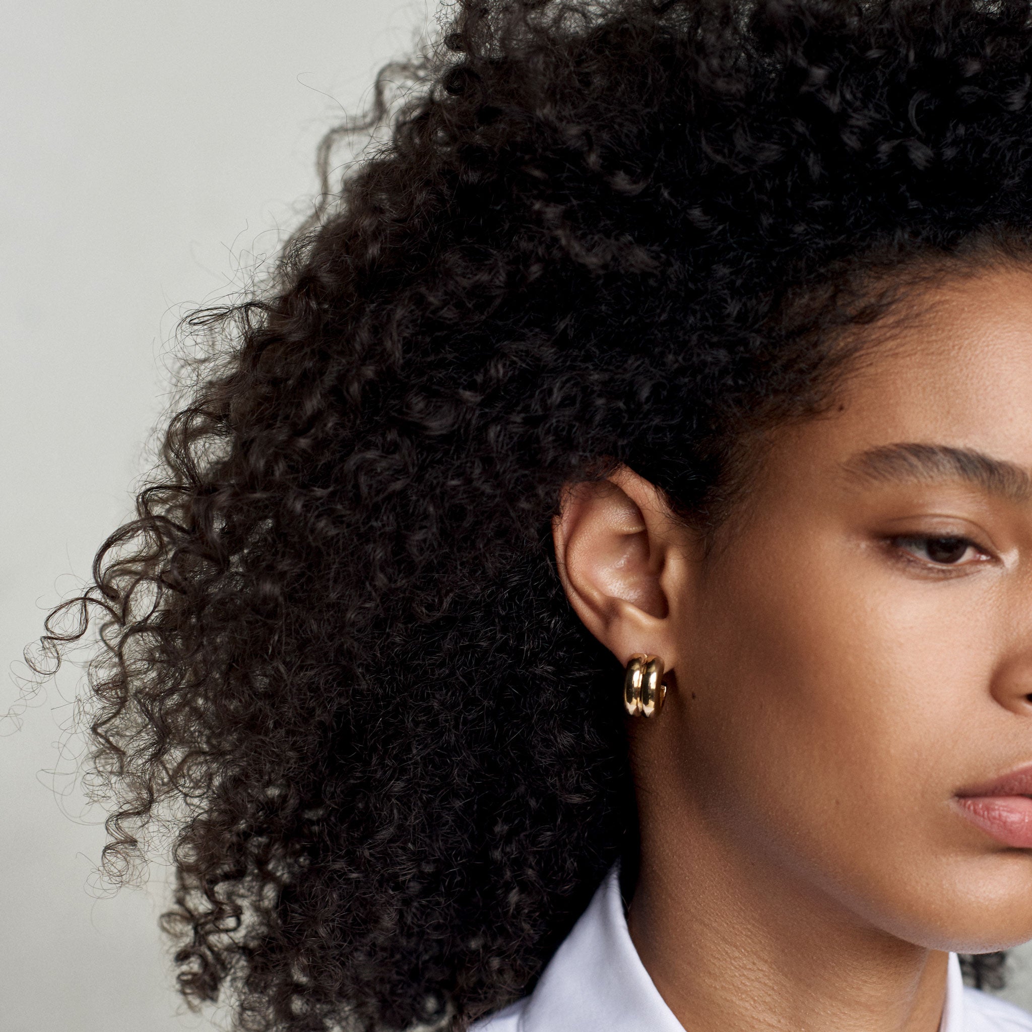 Woman wearing AGMES 18k gold vermeil double ridged small hoop earrings.