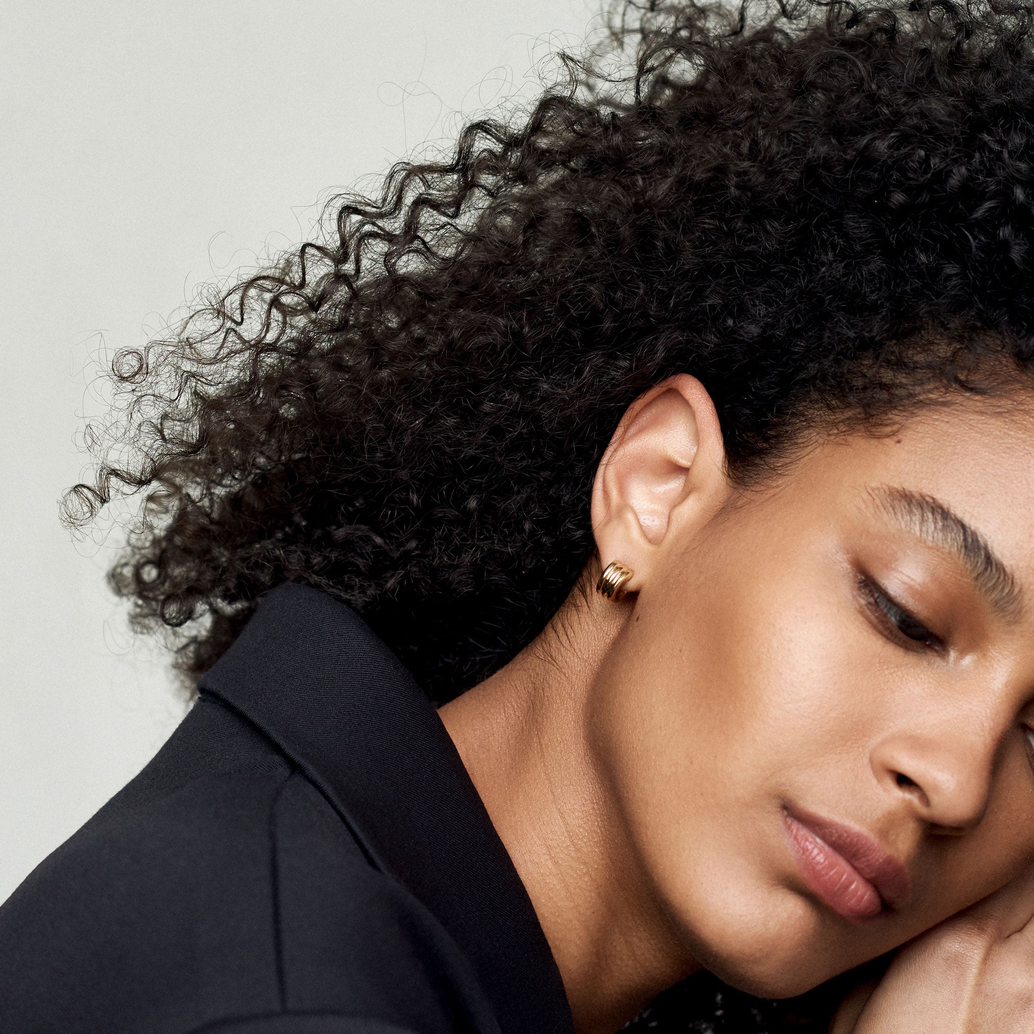 Woman wearing AGMES 18k gold vermeil triple ridged mini hoop earrings.