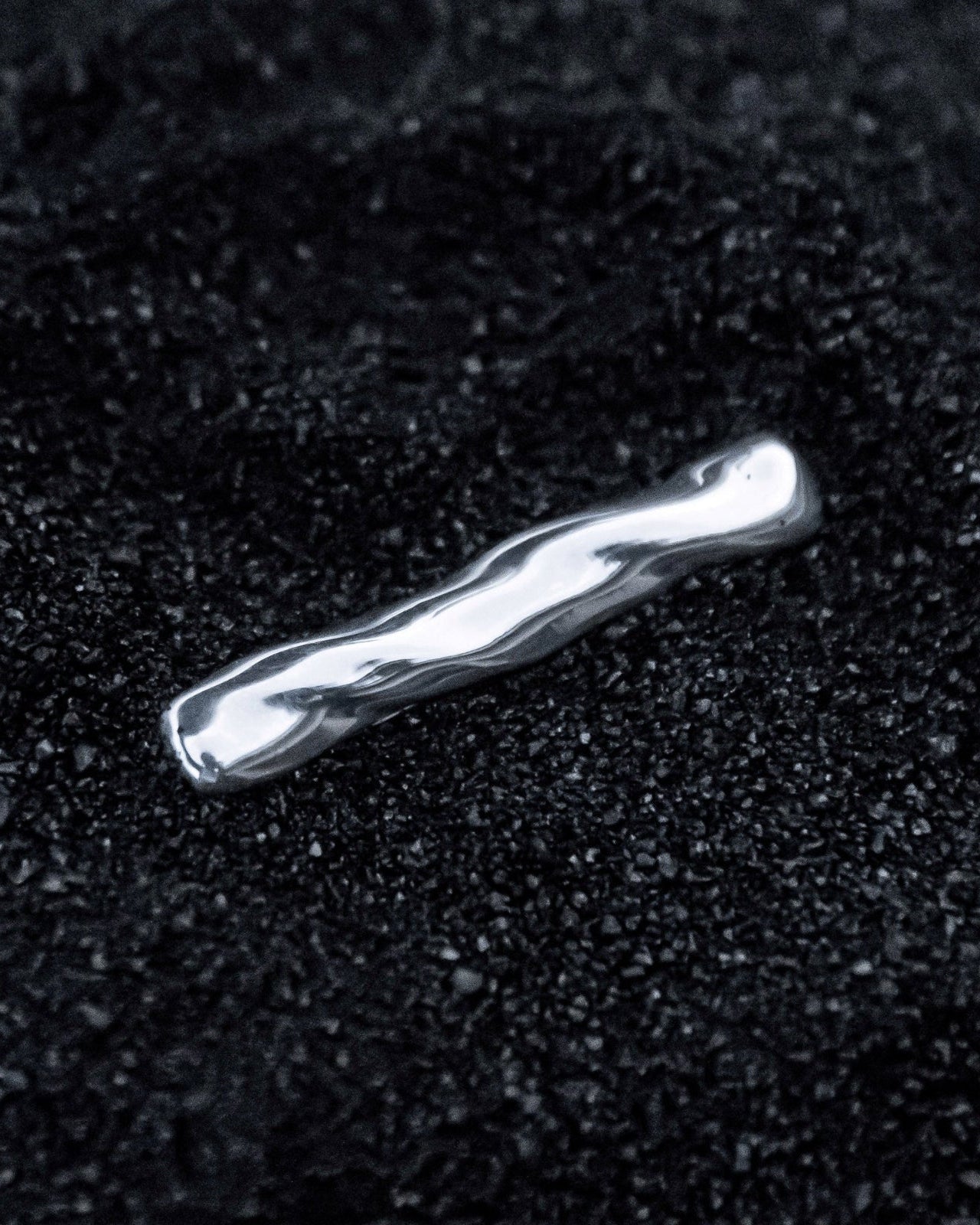 AGMES .925 sterling silver sculptural Astrid Tie Clip on black sand background.