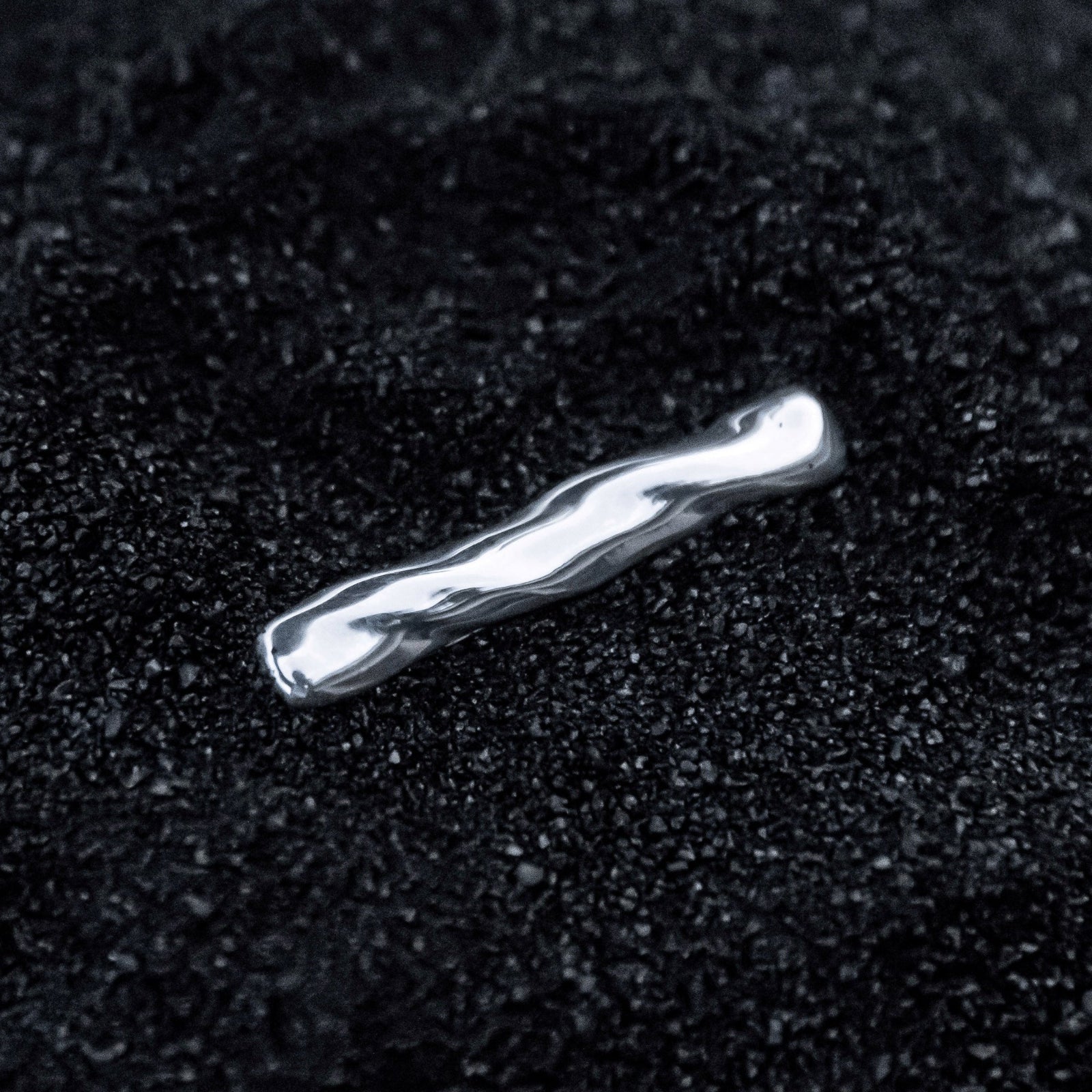 AGMES .925 sterling silver sculptural Astrid Tie Clip on black sand background.