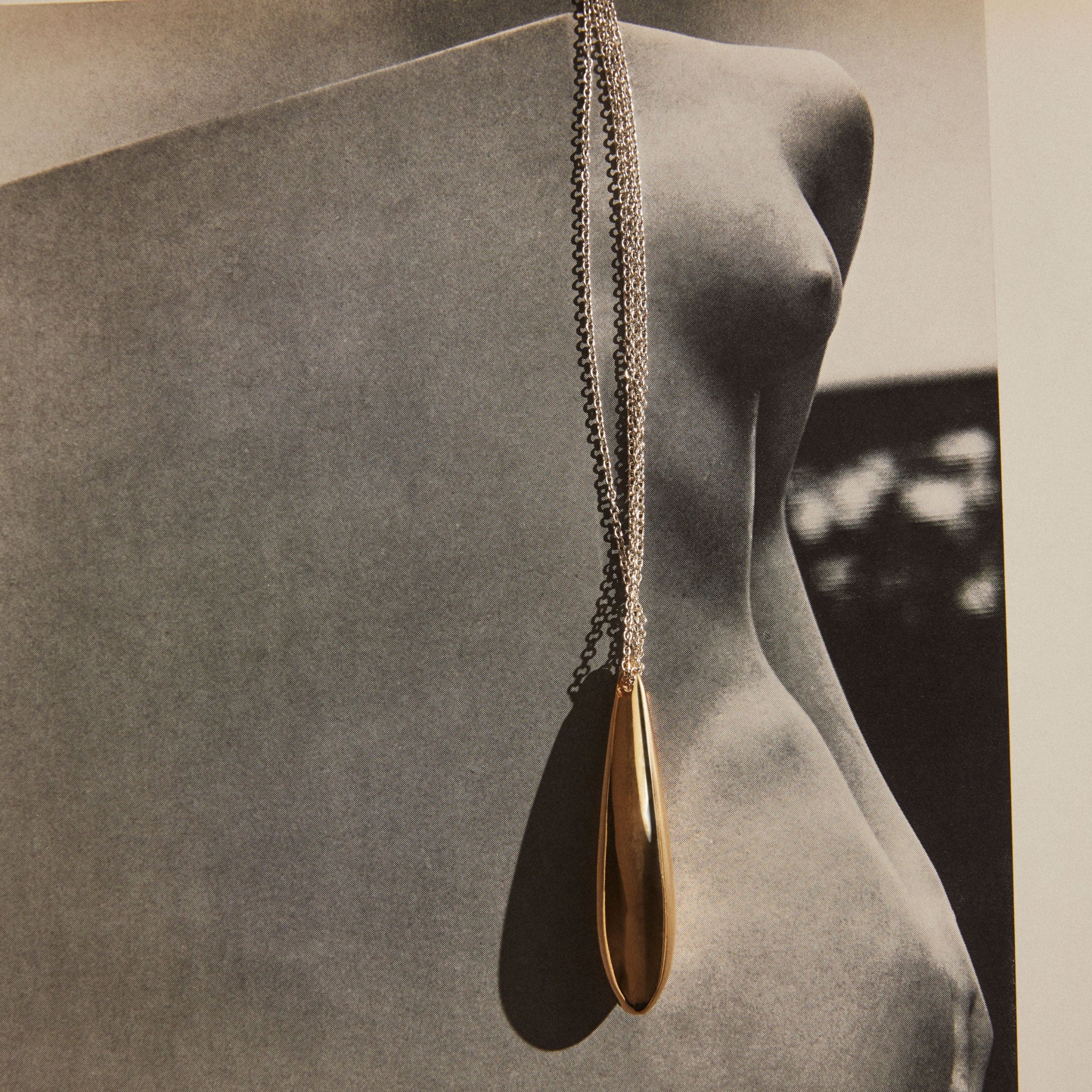 18k Gold Vermeil Double Chain Audrey Pendant laying on magazine, still life