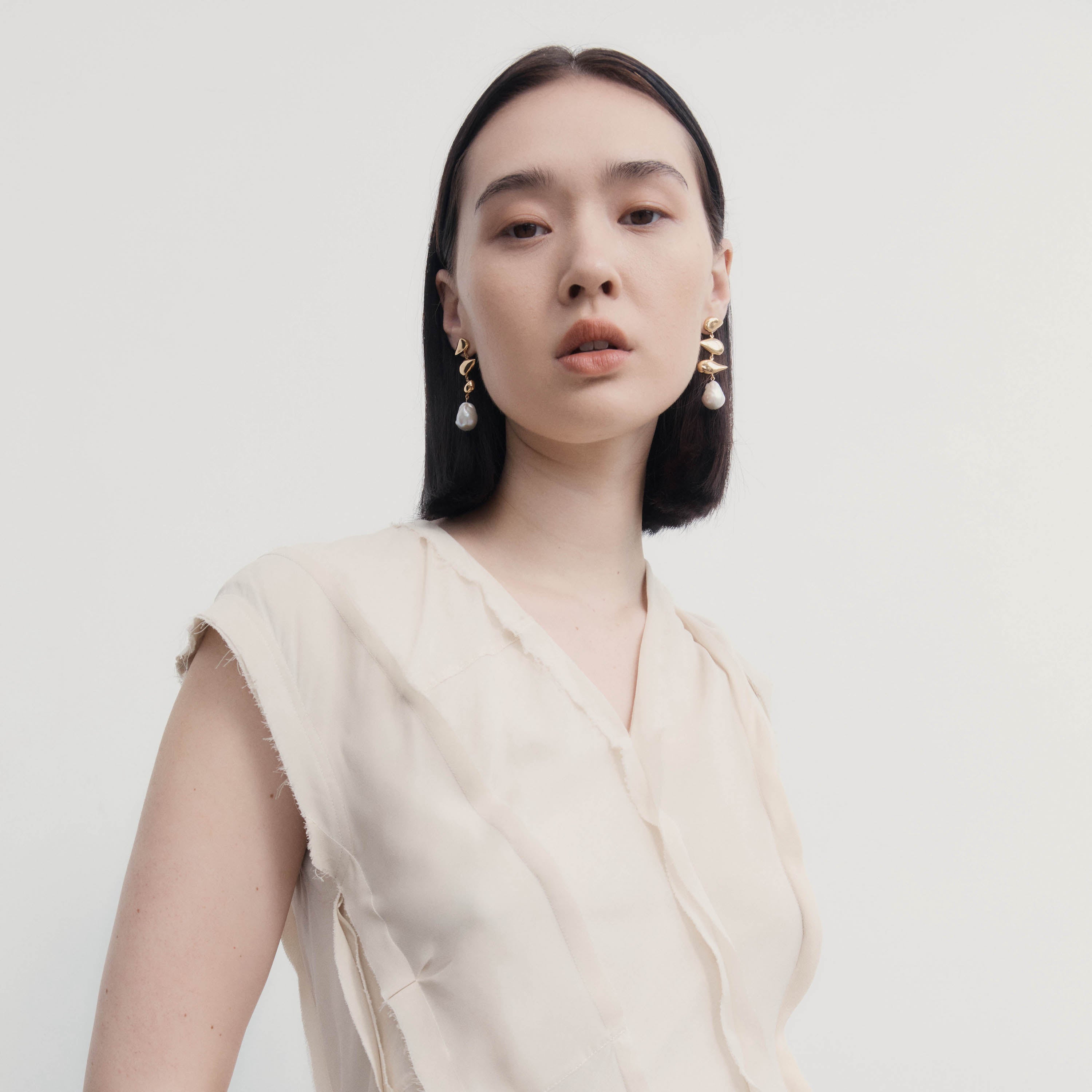 Woman wearing AGMES yellow gold vermeil drop pearl Flora earrings.