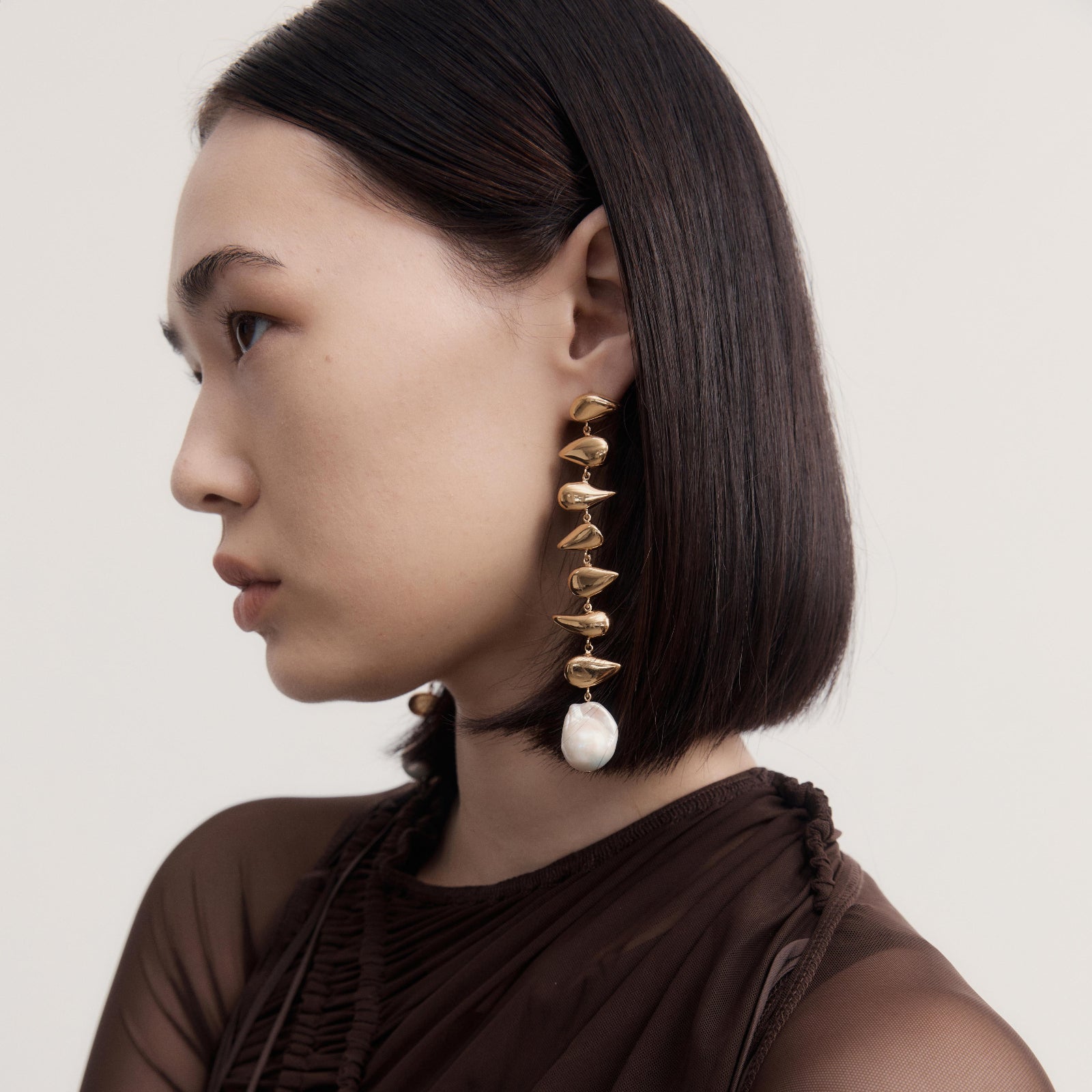 Woman wearing AGMES 18k yellow gold vermeil long drop freshwater pearl Florence earrings.