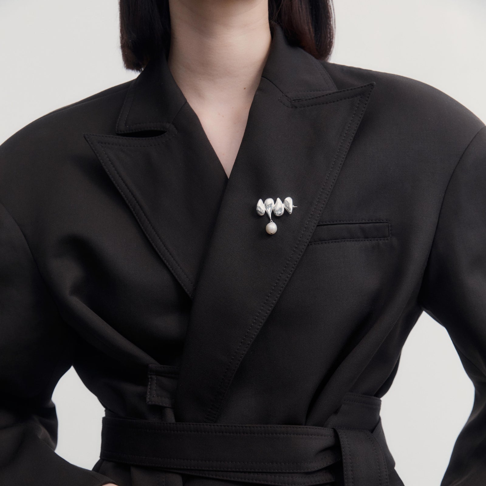 Person wearing AGMES .925 Sterling Silver Joy Brooch with Baroque Pearl Drop on black blazer. 