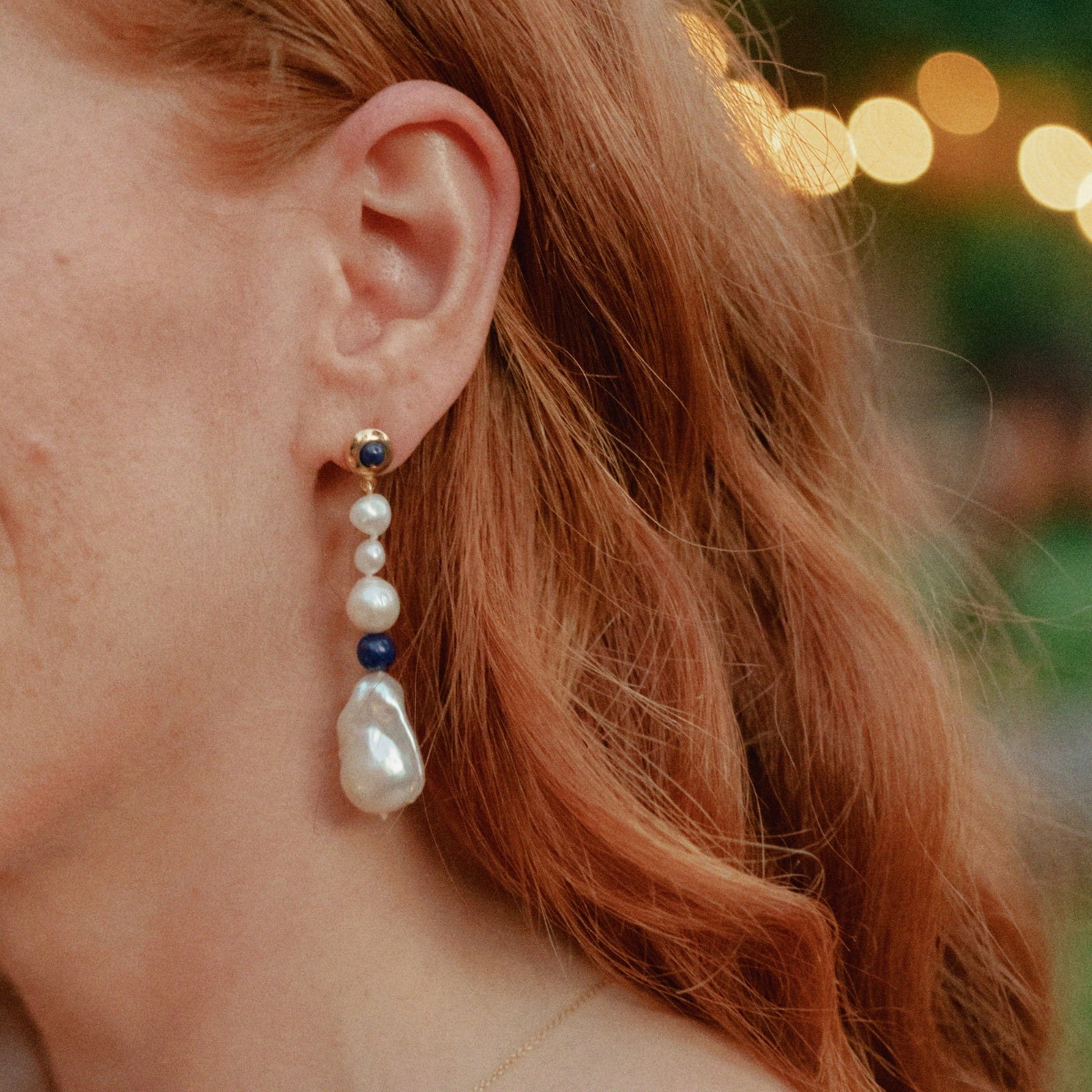Person wearing AGMES 18K Gold Vermeil Kait Earrings with Baroque Pearl and Lapis Stone drop.