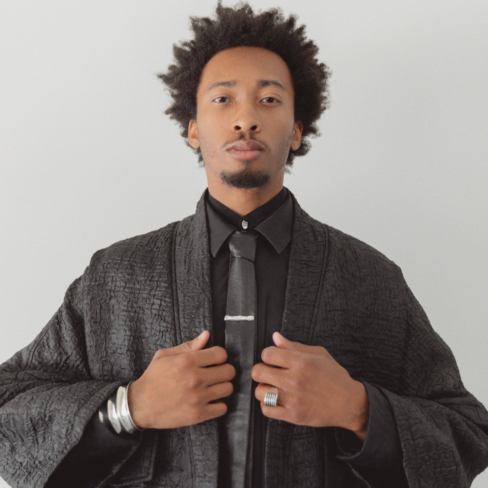 Model wearing AGMES .925 sterling silver Ridge Cuff, Wide Boeri Ring, Astrid Tie Clip, and Sum of Parts Tie Clip.
