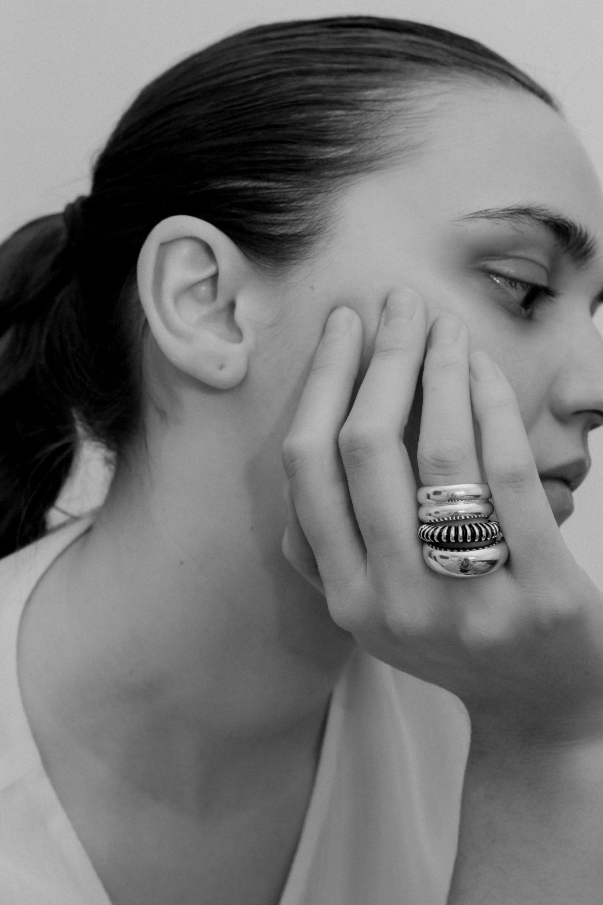 Woman wearing the AGMES .925 Sterling Silver Bertrand Ring, Ridge Ring, and Domed Ring. 