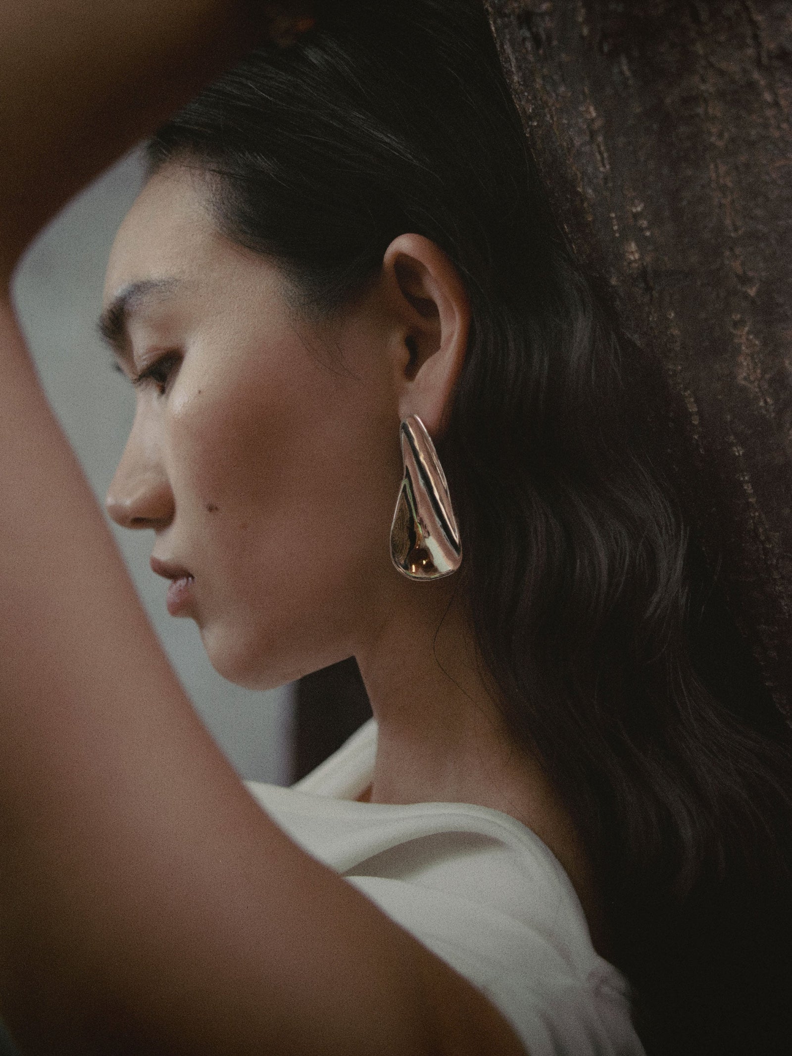 Woman wearing AGMES 0.925 sterling silver long sculpted earrings. 