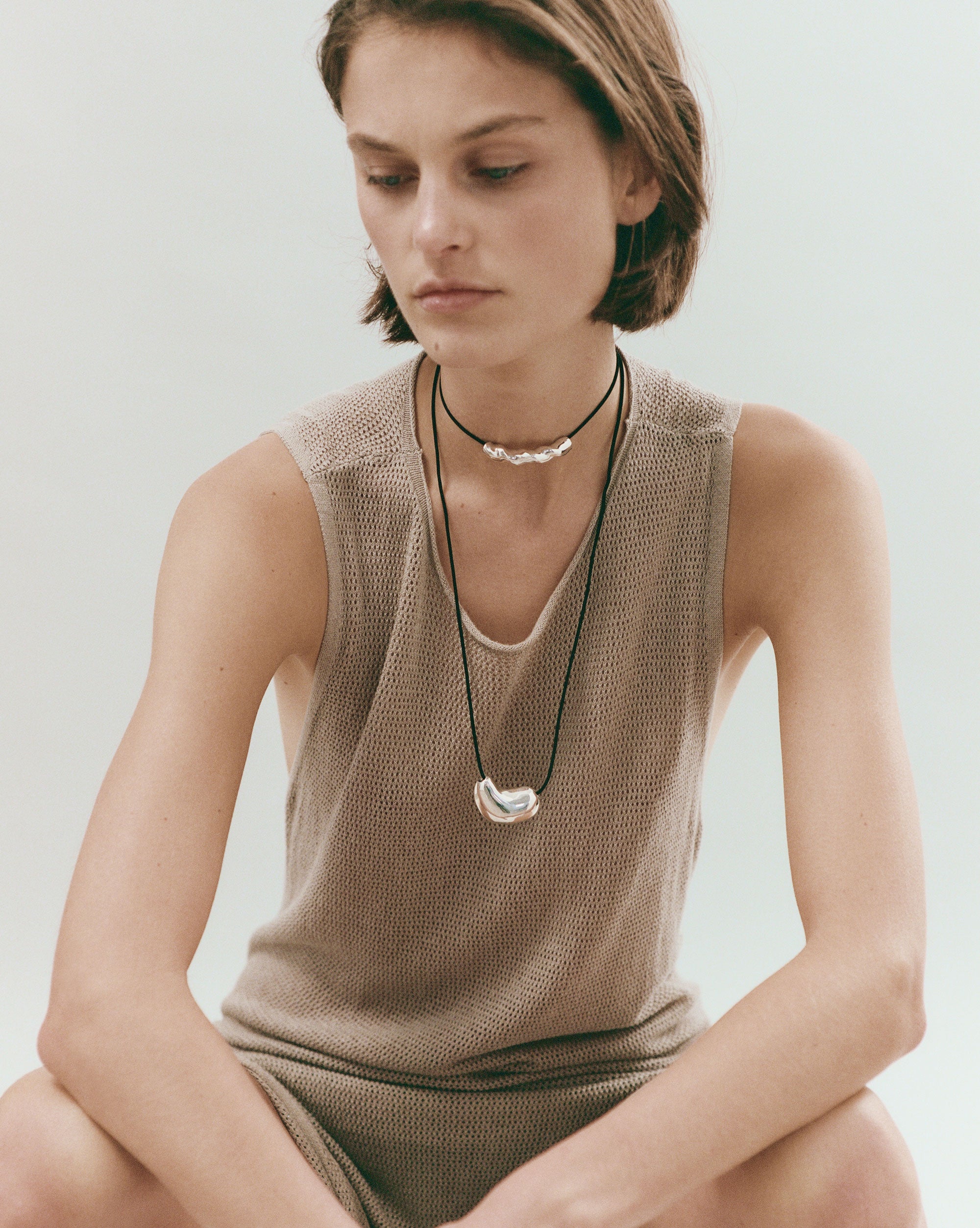 Woman wearing AGMES .925 Sterling Silver Sculpted Heart Pendant and Small Astrid Pendant on Black Suede Cord. 