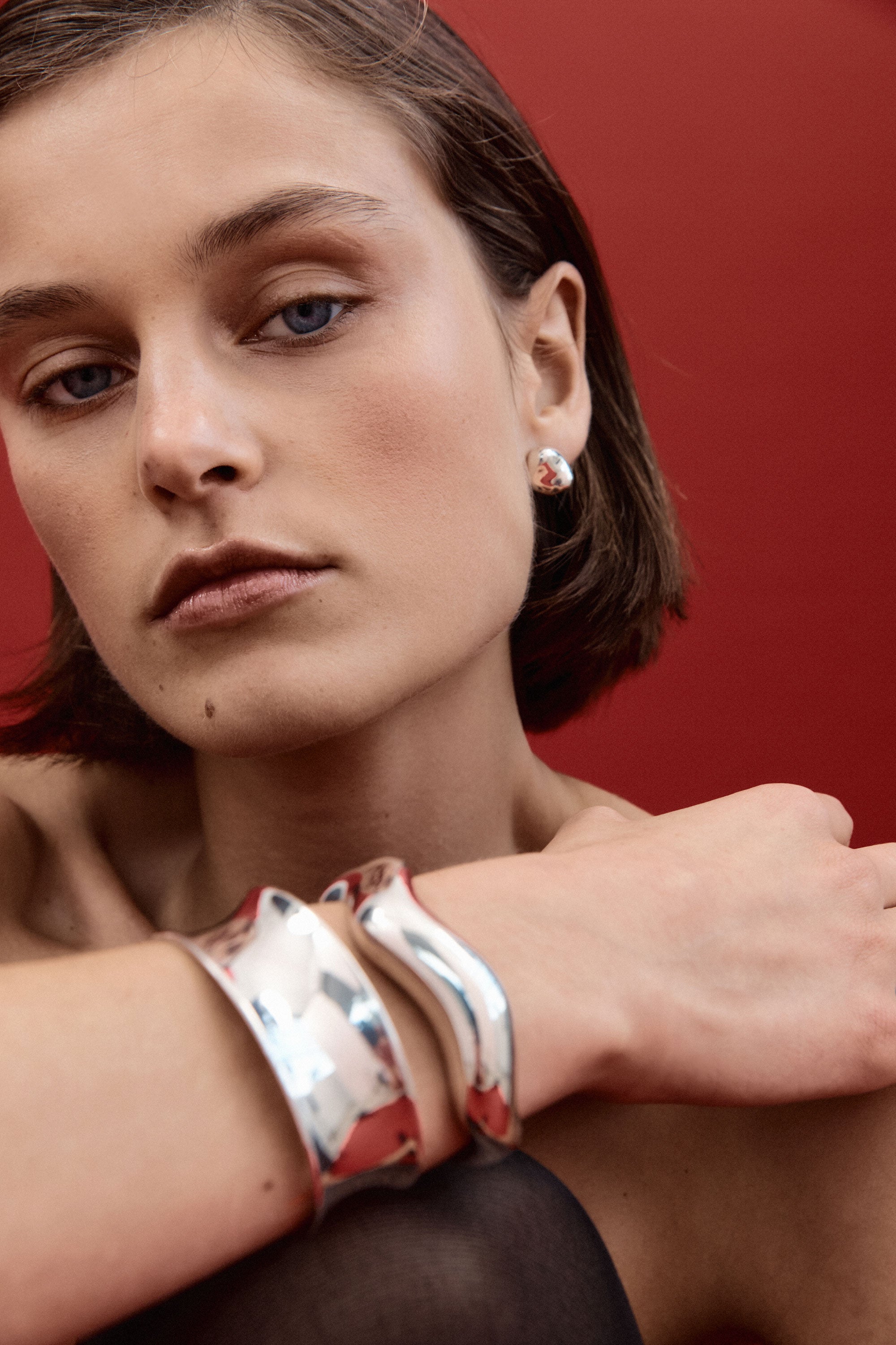 Woman wearing AGMES 0.925 sterling silver sculpted round stud earrings.