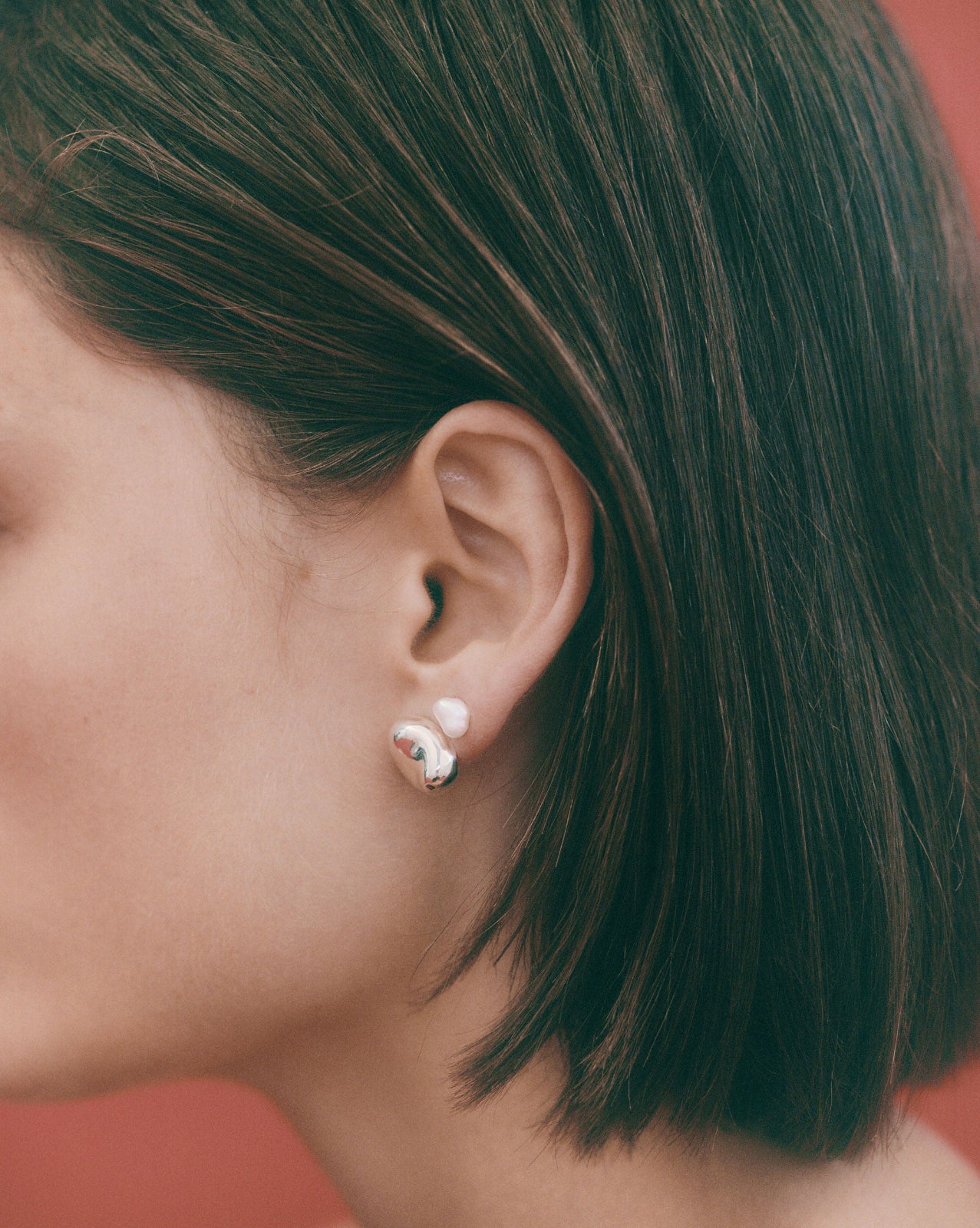 Person wearing AGMES pearl stud earrings.