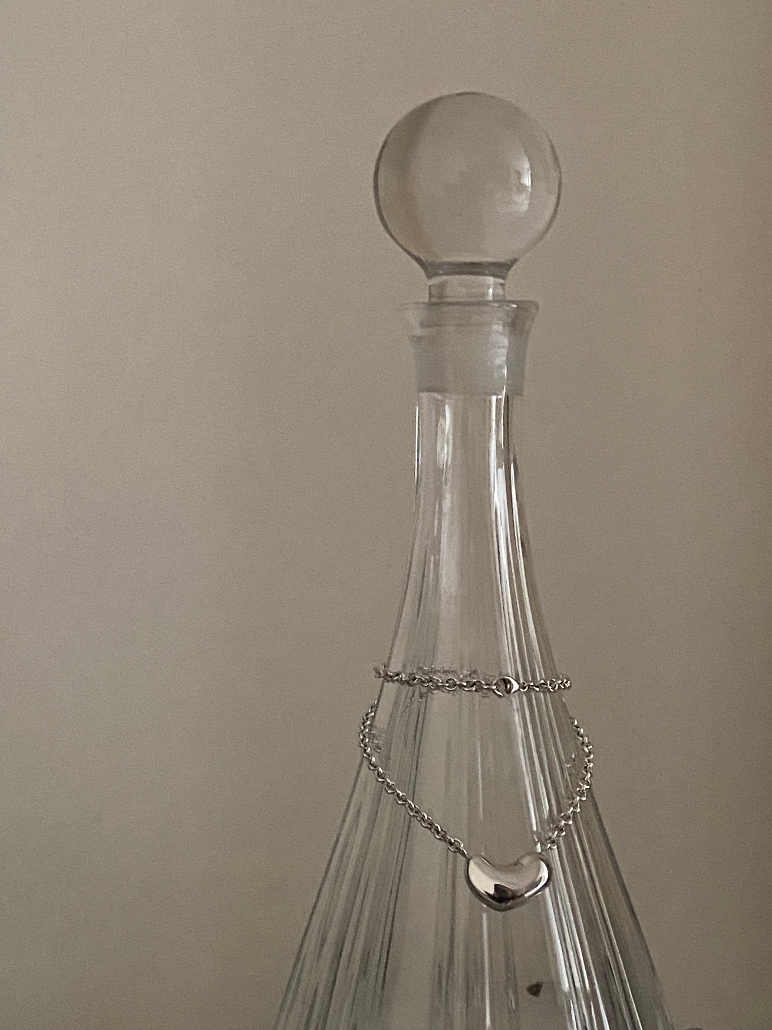 AGMES .925 Sterling Silver Small Sculpted  Heart Pendant II on chain necklace displayed on glass vase. 