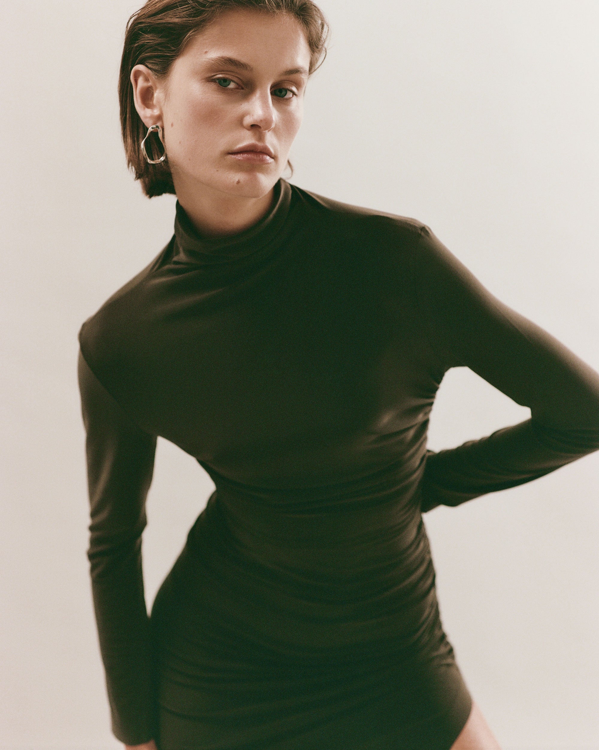 Woman wearing AGMES 18k gold vermeil sculptural wavy small round hoop earrings.