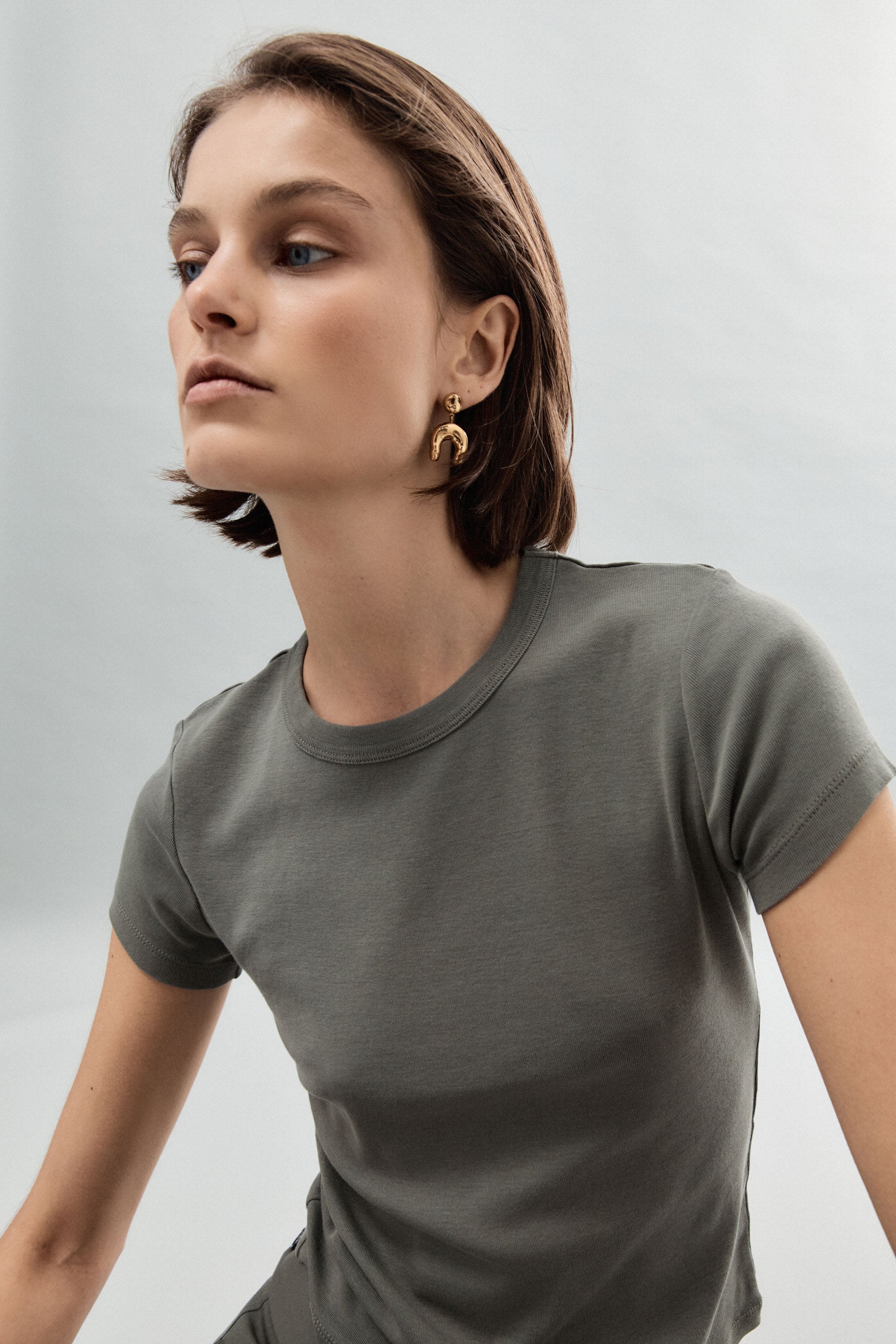 Woman wearing AGMES 18k gold vermeil earrings with sculpted wishbone drop.