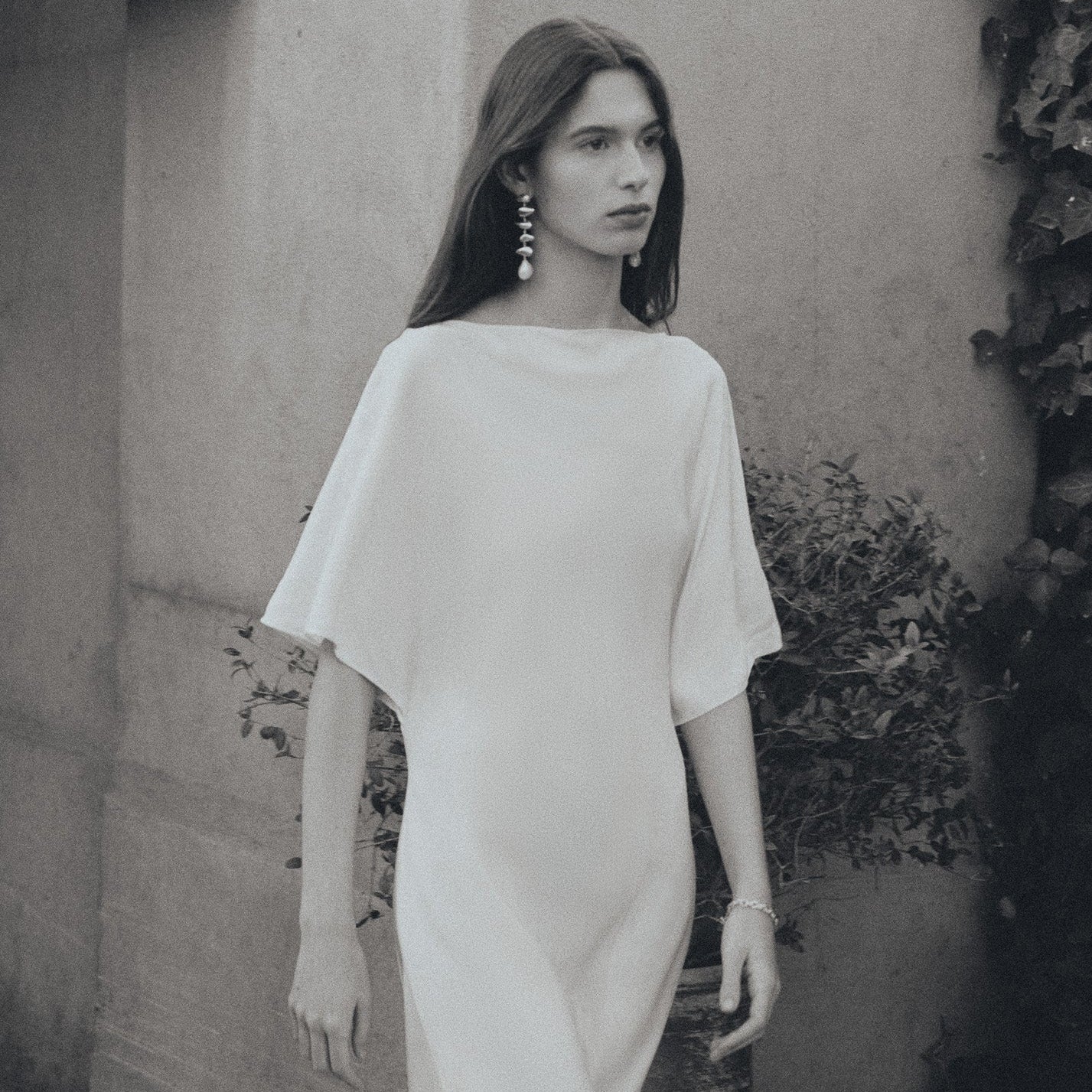 Model wearing AGMES .925 sterling silver and freshwater pearl sculptural tiered drop Long Flora Earrings. Black and white image.