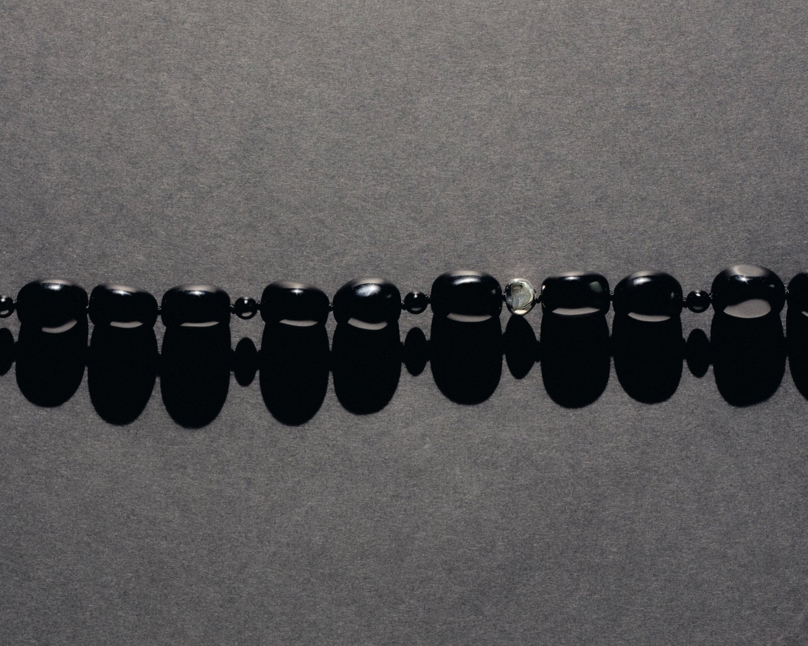 Black onyx beaded necklace with .925 sterling silver accent on grey background