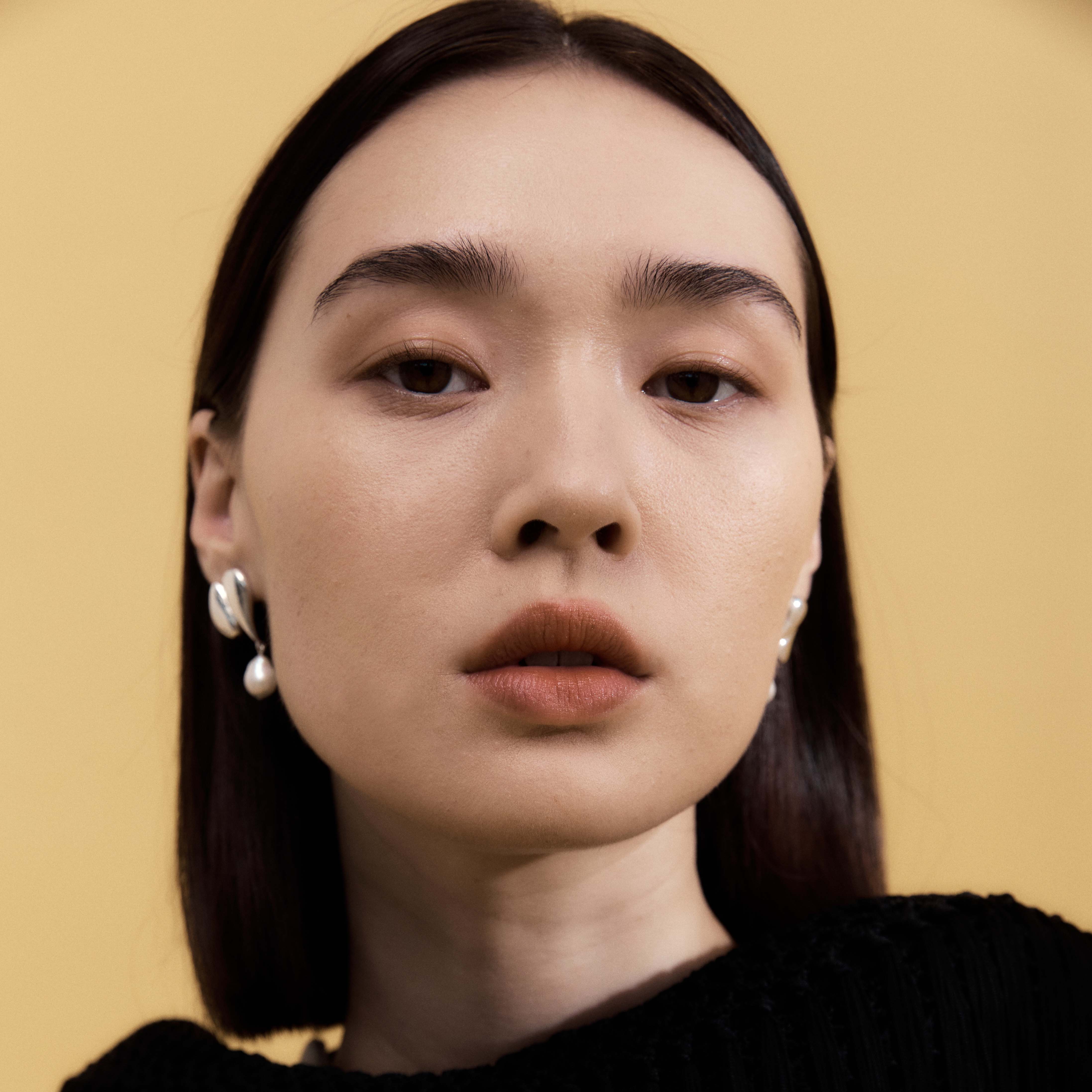 Woman wearing AGMES 0.925 sterling silver drop pearl Elvira earrings.