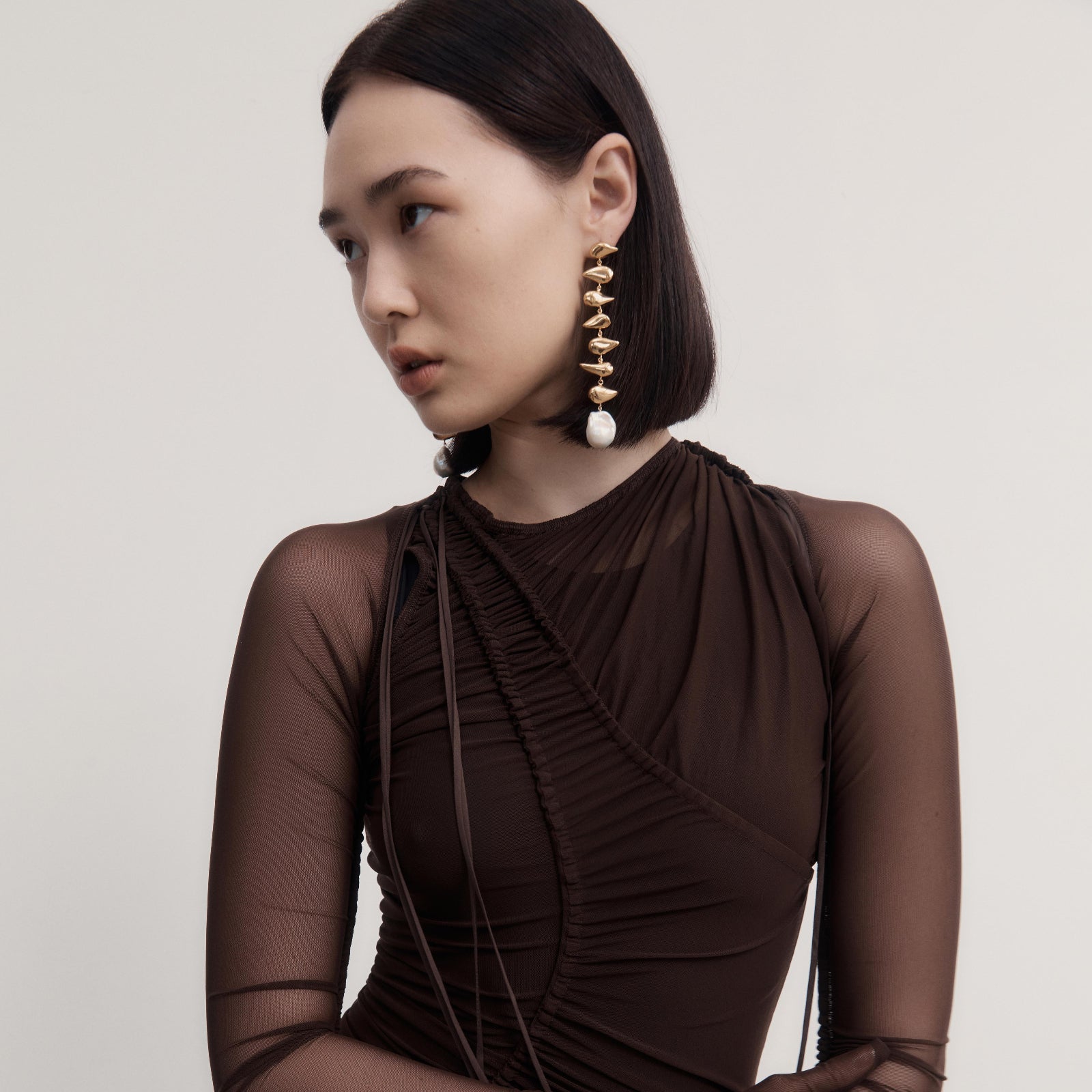 Woman wearing AGMES 18k yellow gold vermeil long drop pearl Florence earrings.