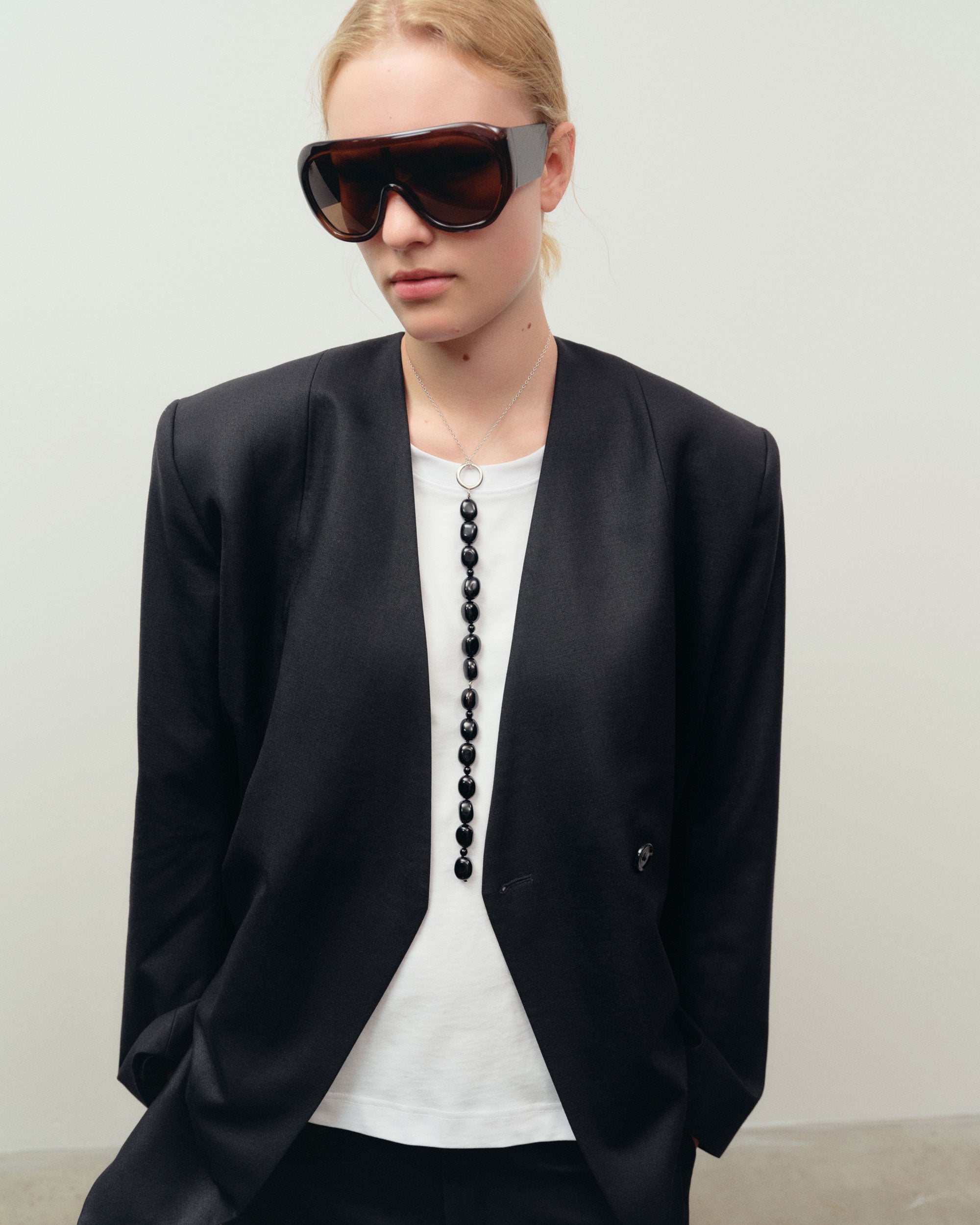 Black Onyx beaded pendant drop necklace on sterling silver chain on woman wearing white shirt and black blazer