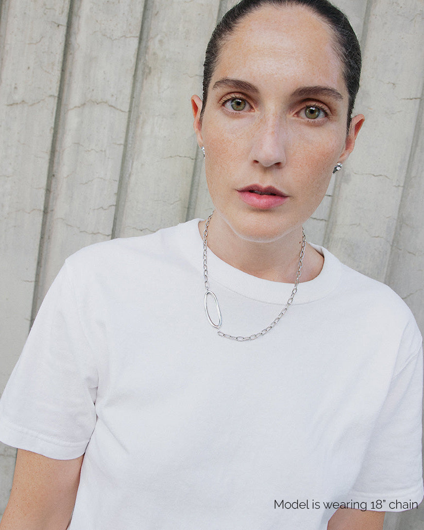 Model wearing AGMES .925 sterling silver 18 inch paperclip infinity Gabriel Chain Necklace featuring statement oval focal link with white shirt.